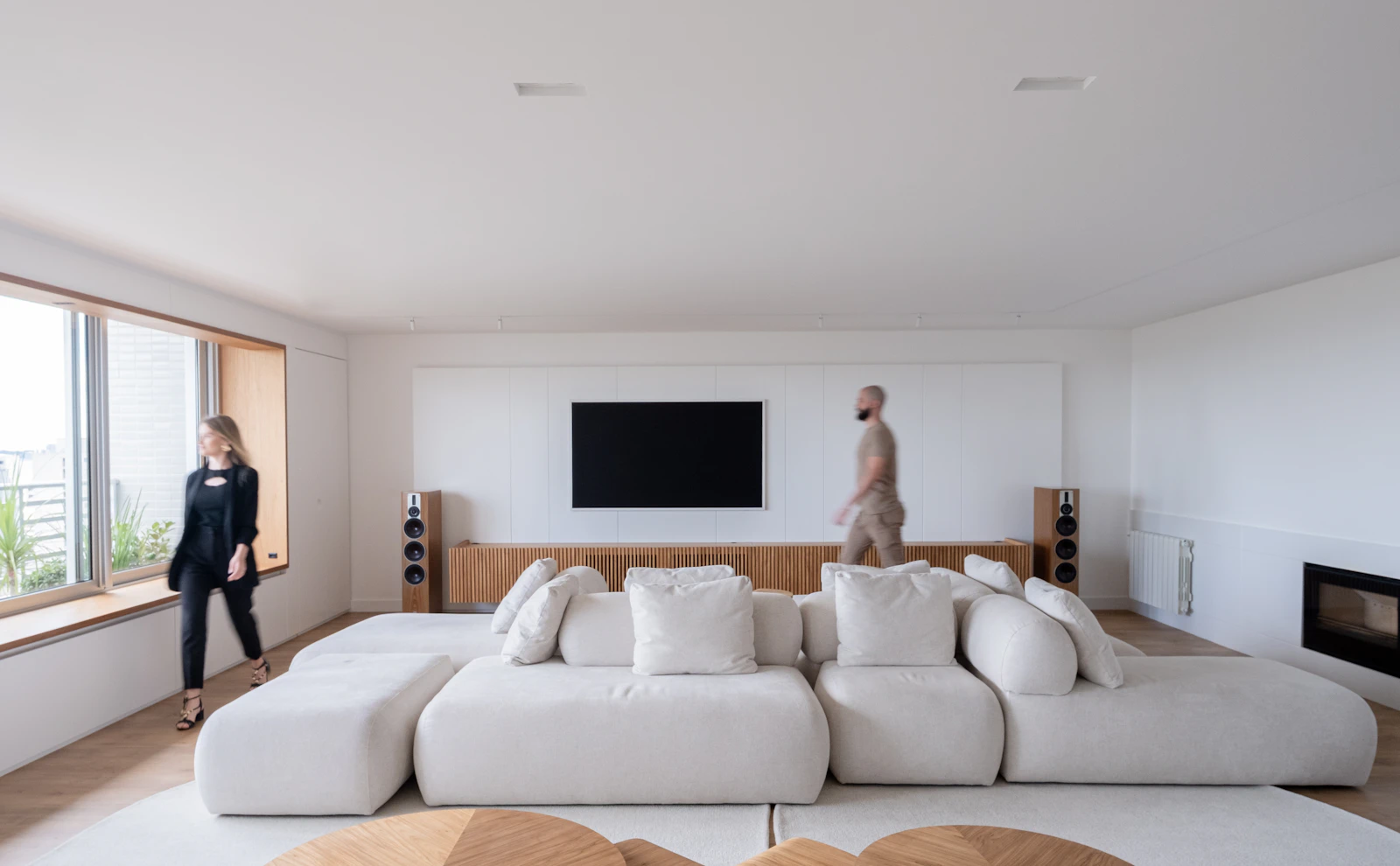 Duas pessoas em uma sala de estar ampla de um imóvel contemporâneo.