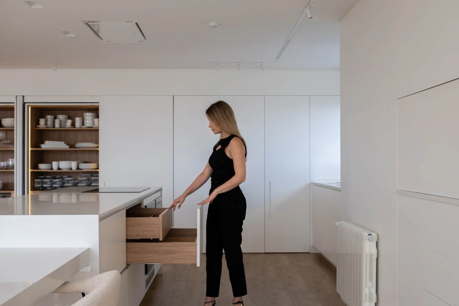 Woman opening an organized kitchen cabinet drawer in a warm modern kitchen