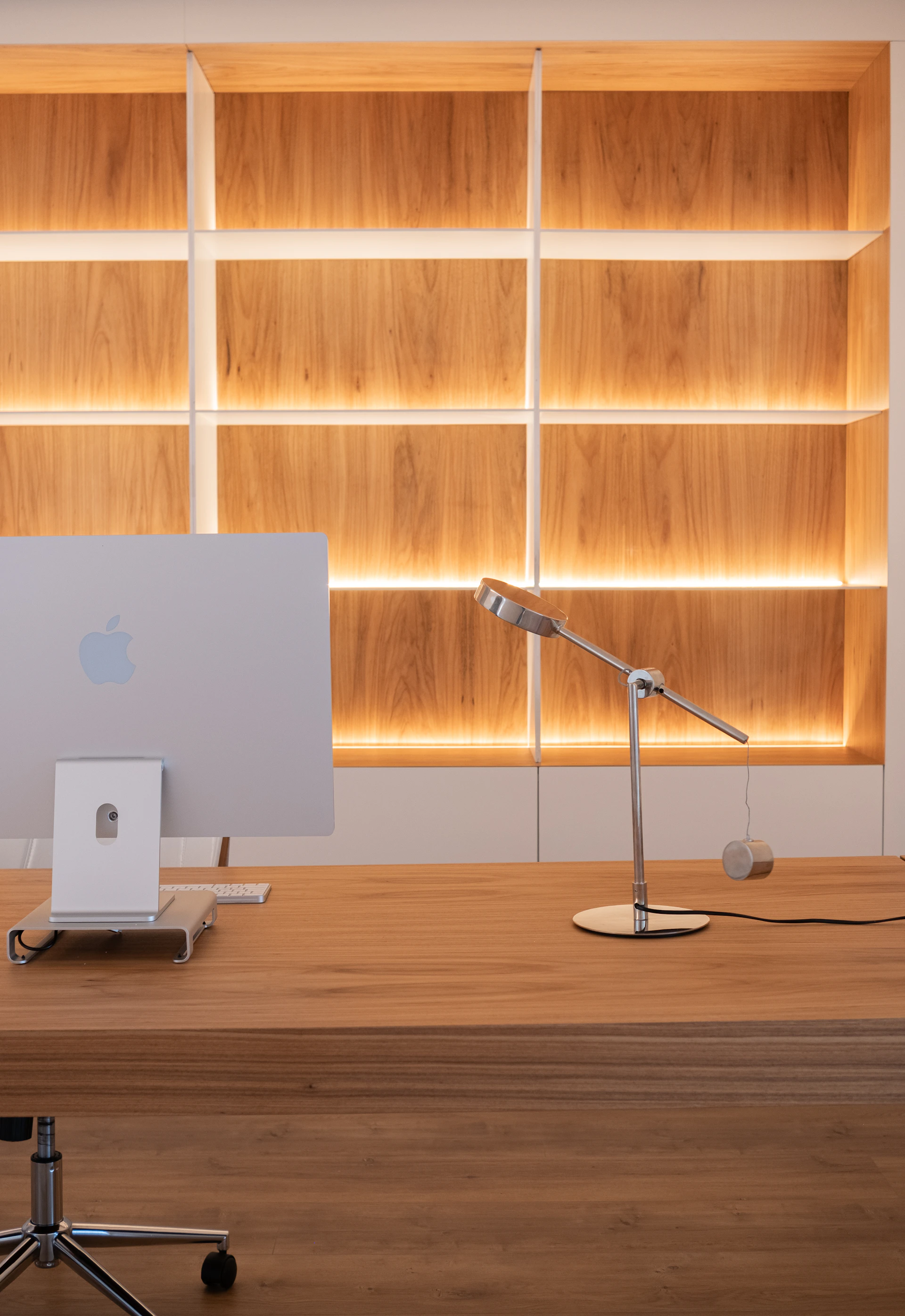 Modern desk with computer and illuminated shelves