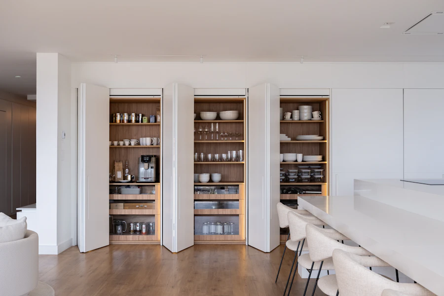 A modern built-in pantry with open doors and neatly arranged shelves