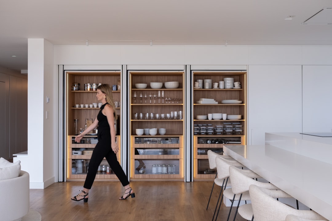 Woman walking past modern built-in shelving in a kitchen