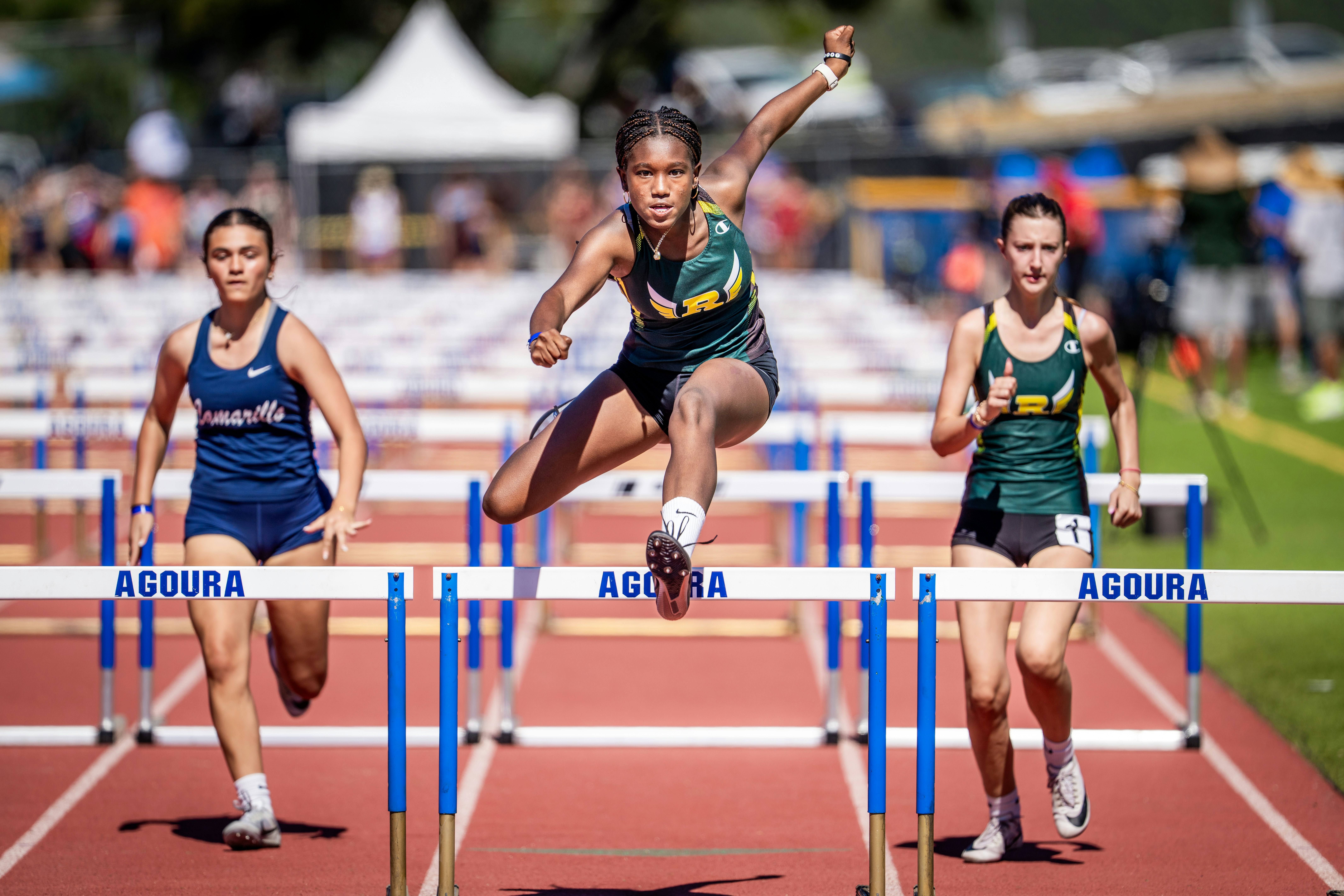 Athletes competing in a hurdle race on a track.