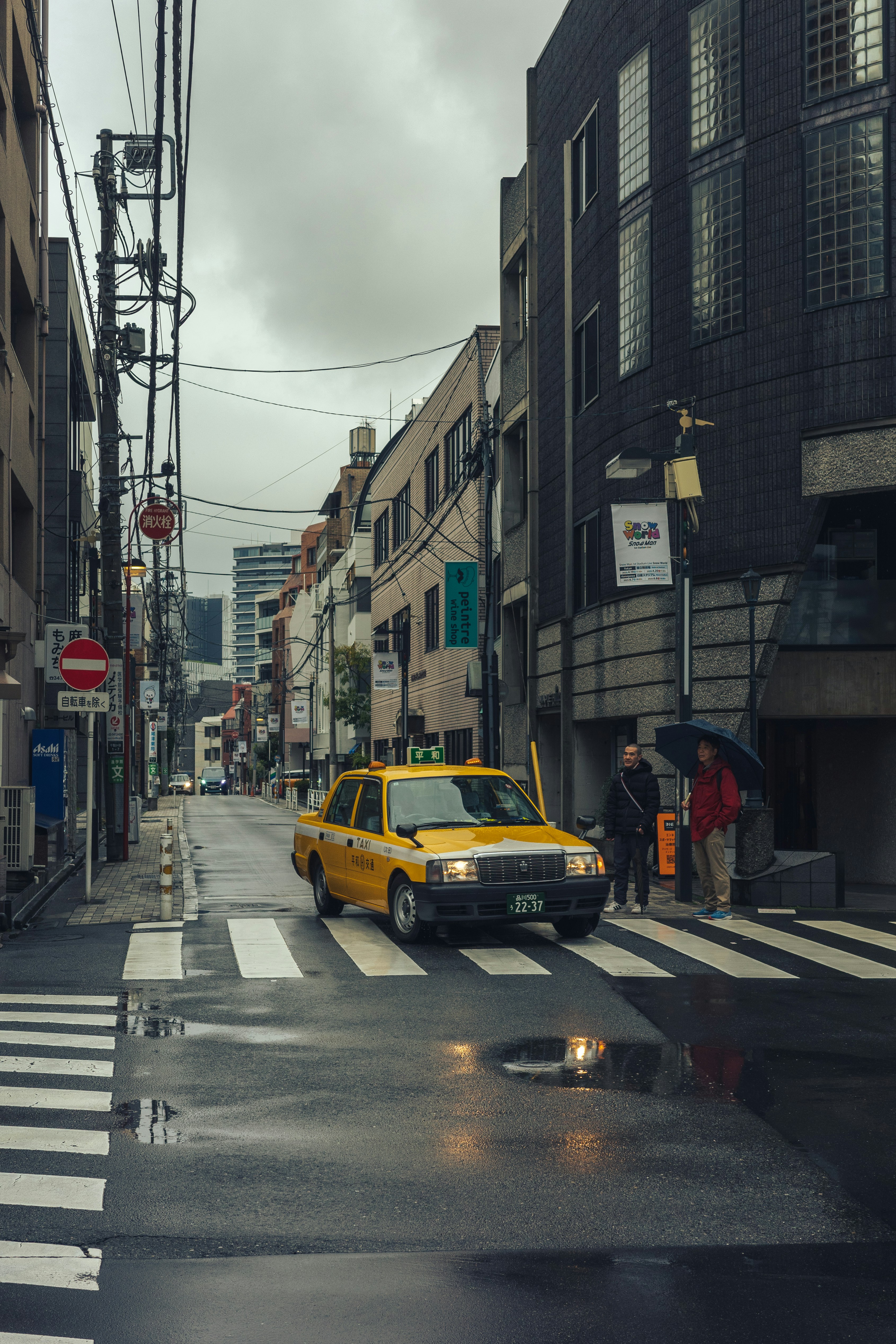 Yellow taxi drives on wet city street