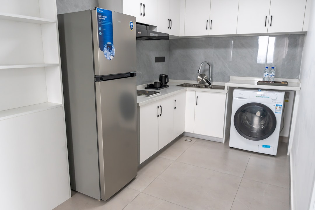 Modern kitchen with stainless steel refrigerator and washing machine.