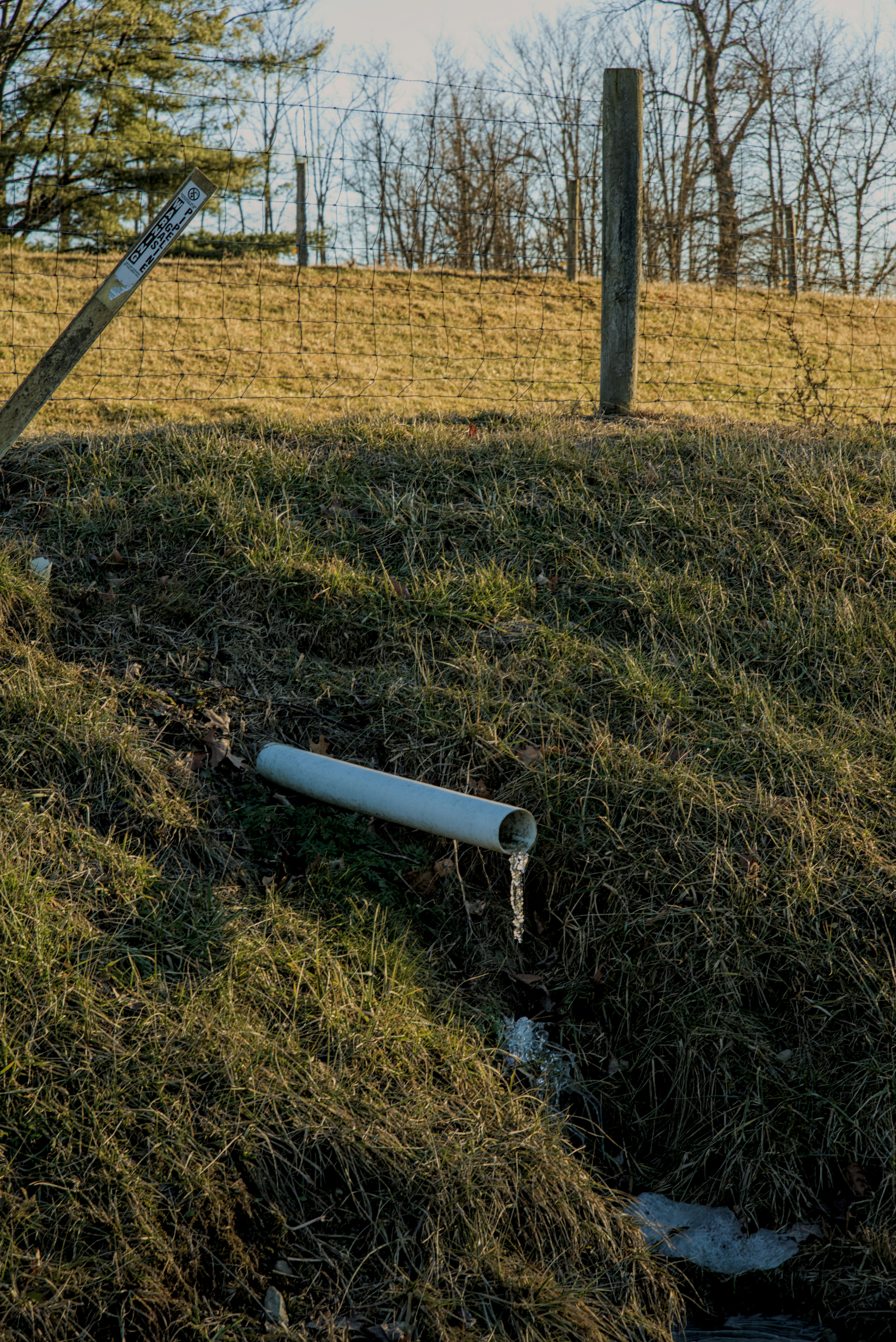 A pipe draining water down a grassy embankment.