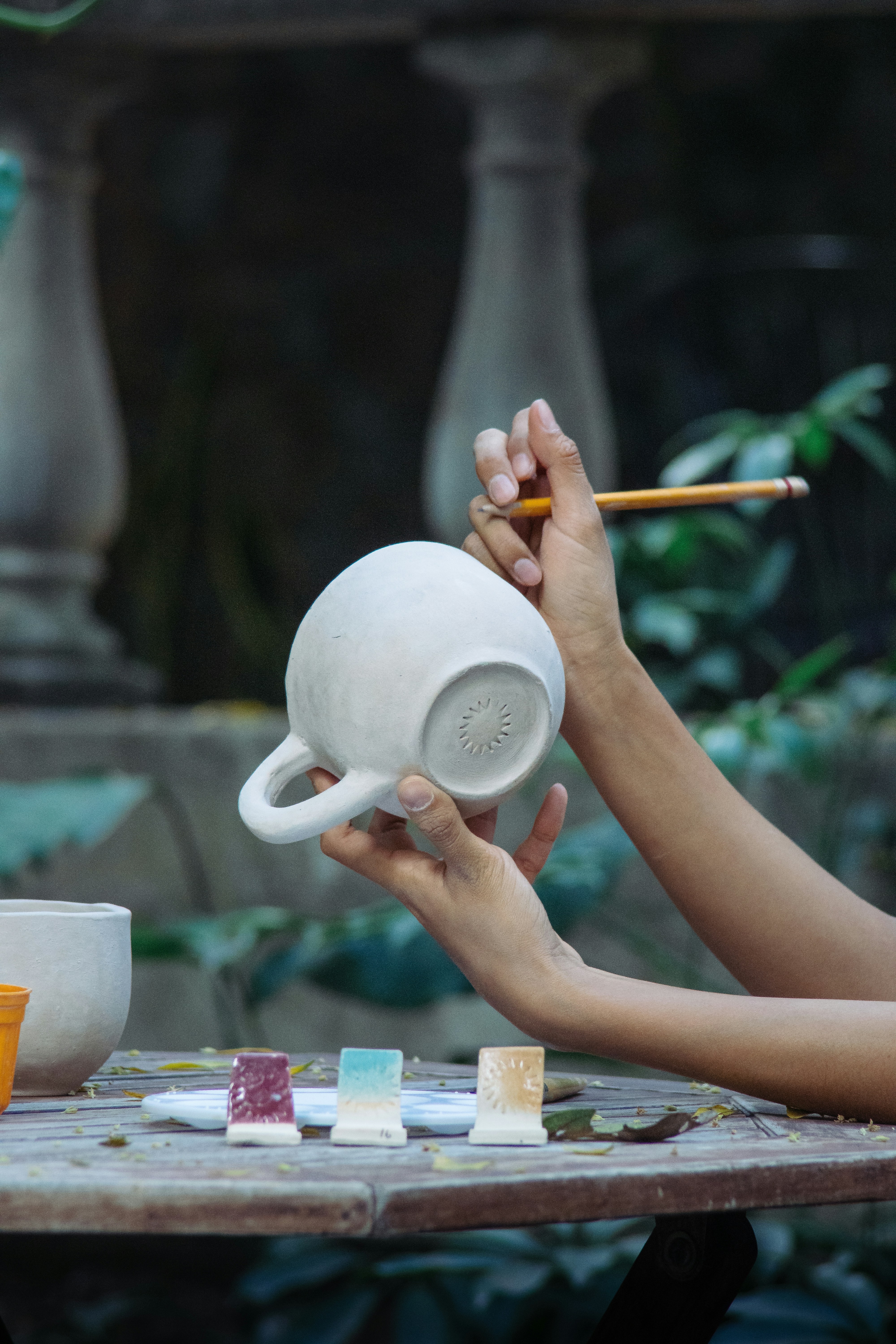 Hände, die eine Keramiktasse mit einem Bleistift bemalen