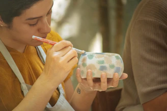Woman painting a patterned ceramic bowl with a brush