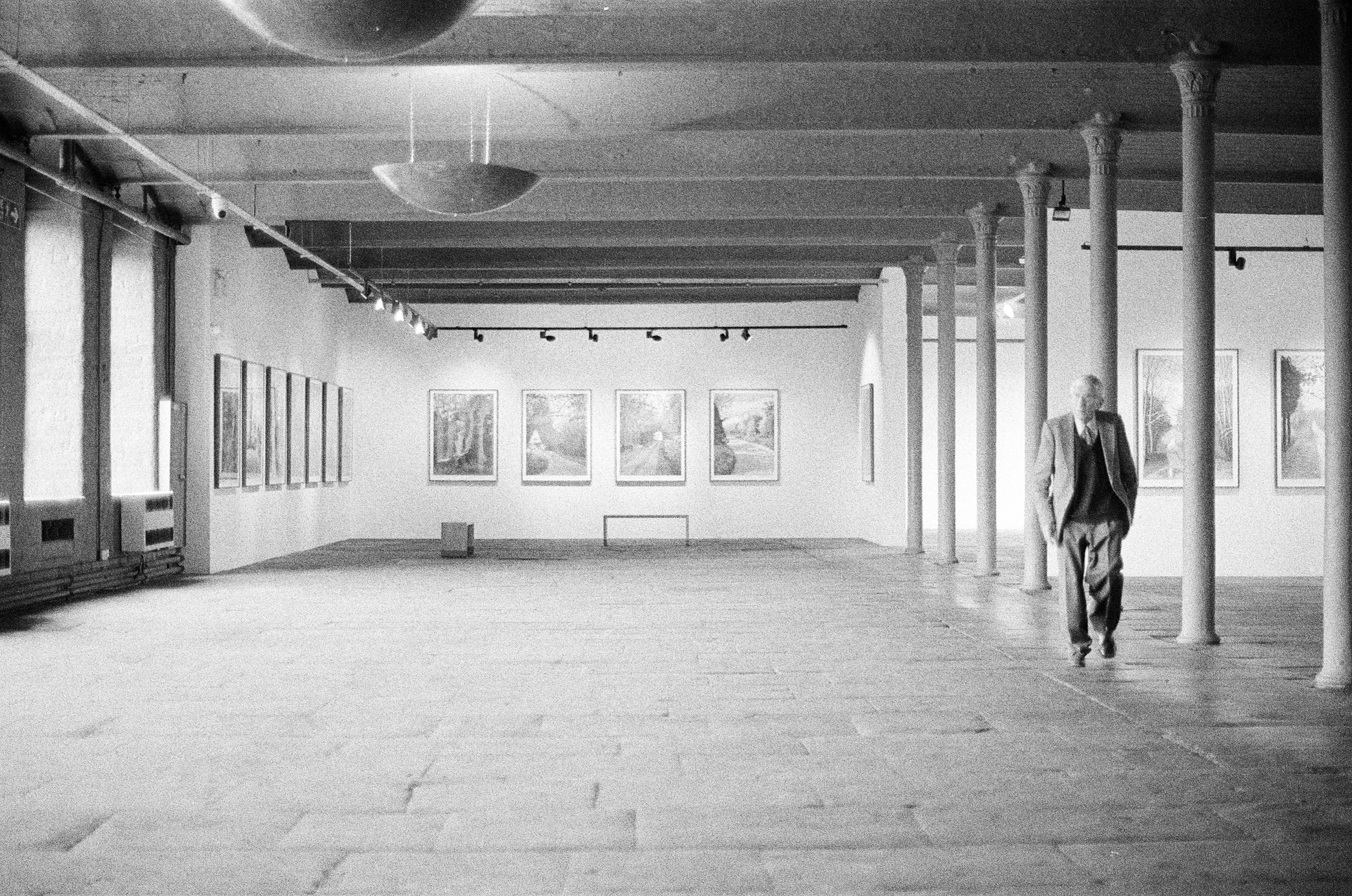 Single visitor walking through a large institutional art gallery