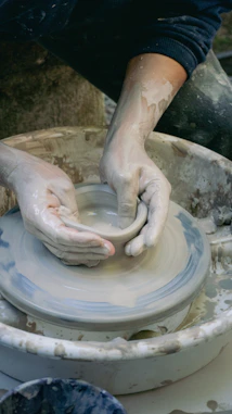 Hands shaping clay on a pottery wheel