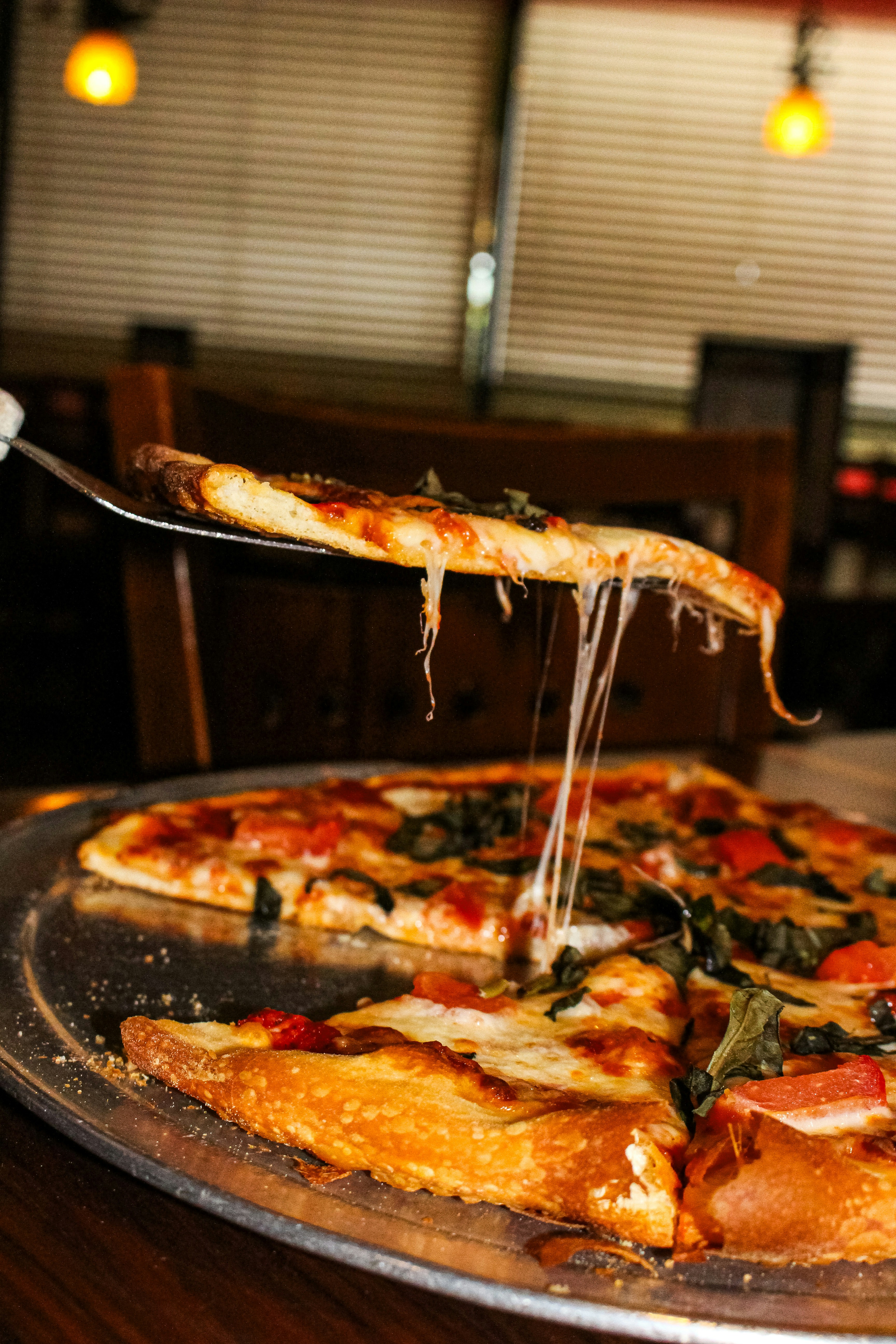 A slice of pizza with melted cheese being lifted