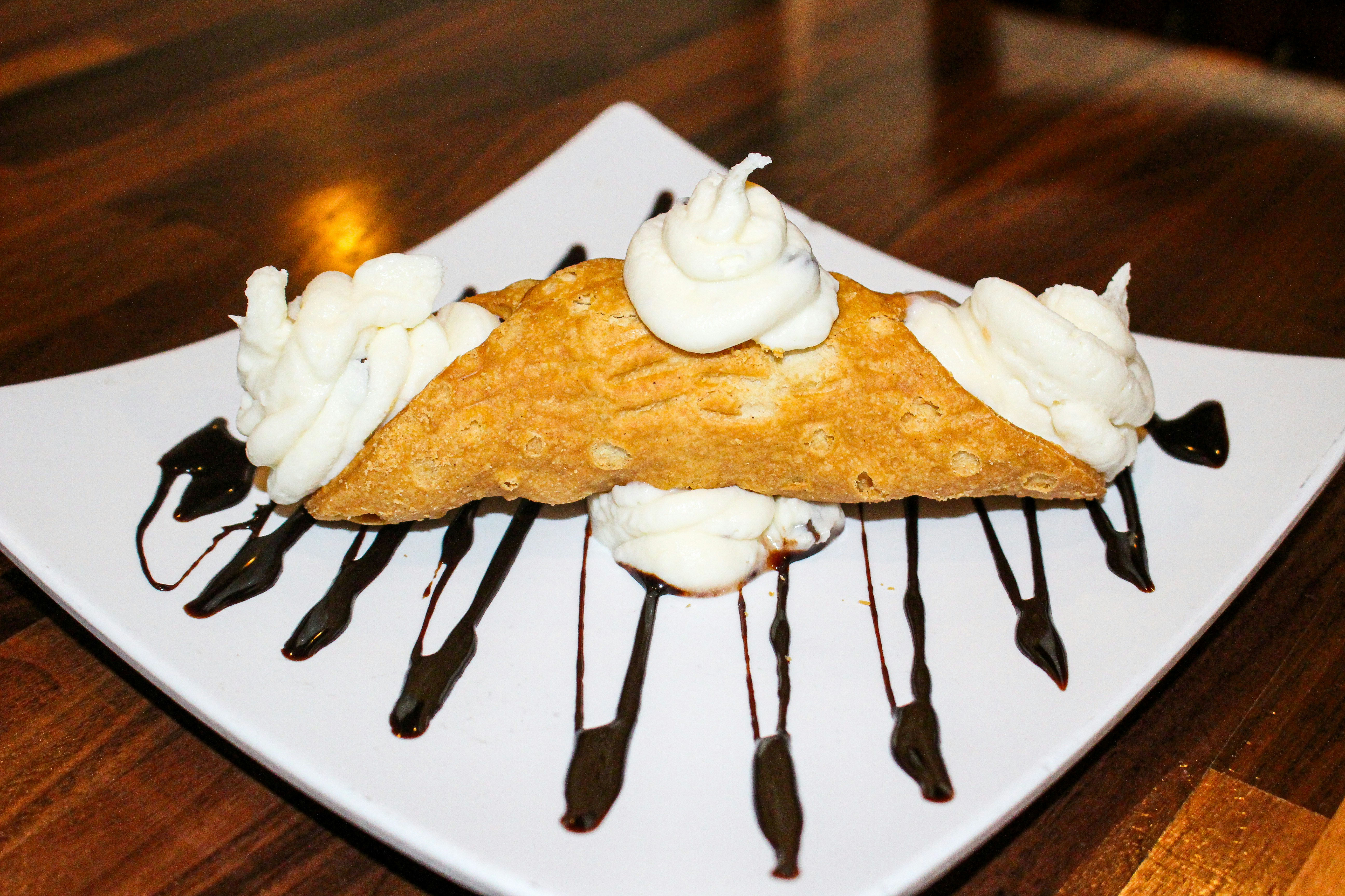 Cannoli with whipped cream and chocolate sauce on plate