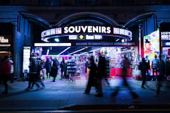 People walking past a brightly lit souvenir shop at night.