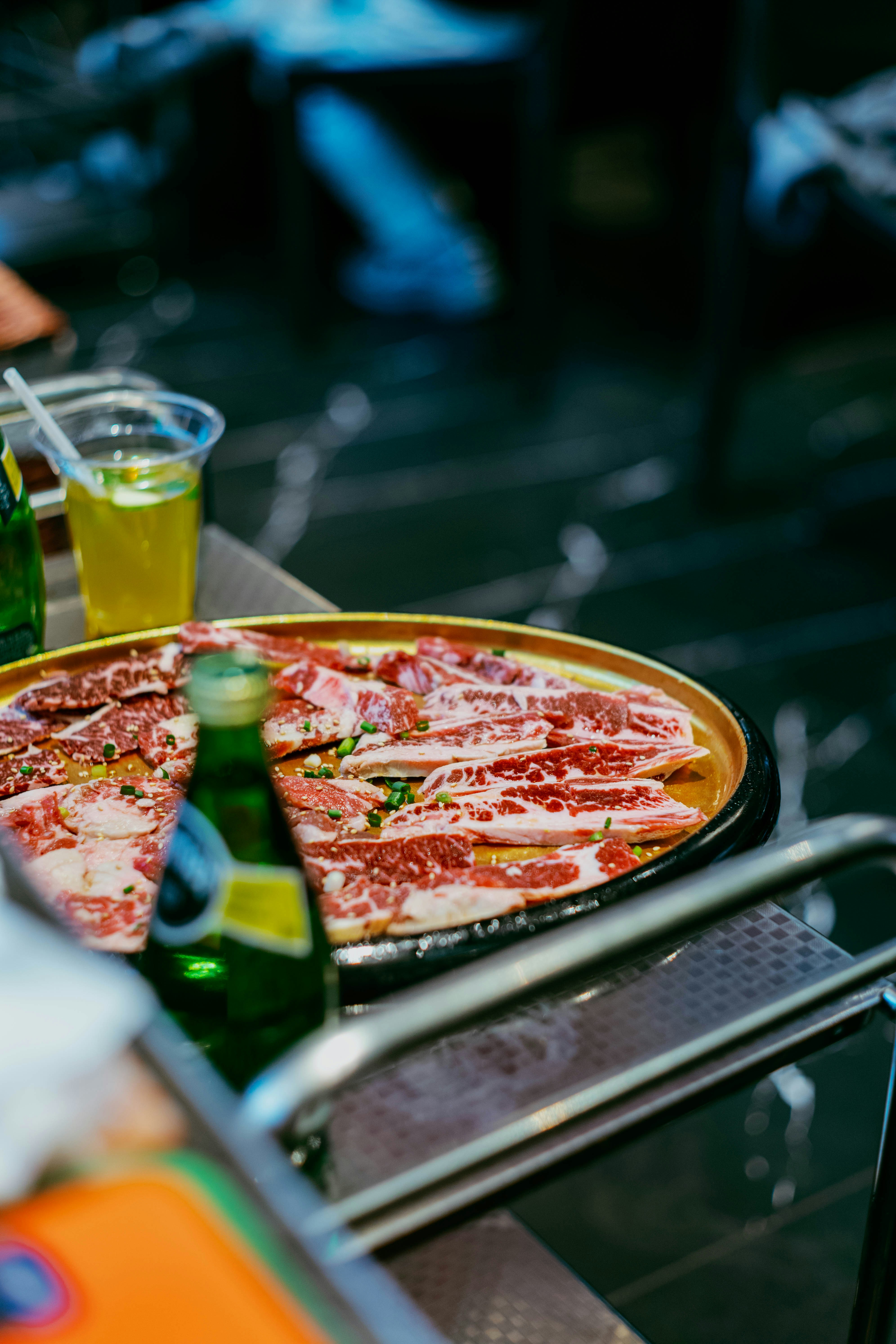 Des tranches de viande crue disposées sur un plateau avec des boissons.