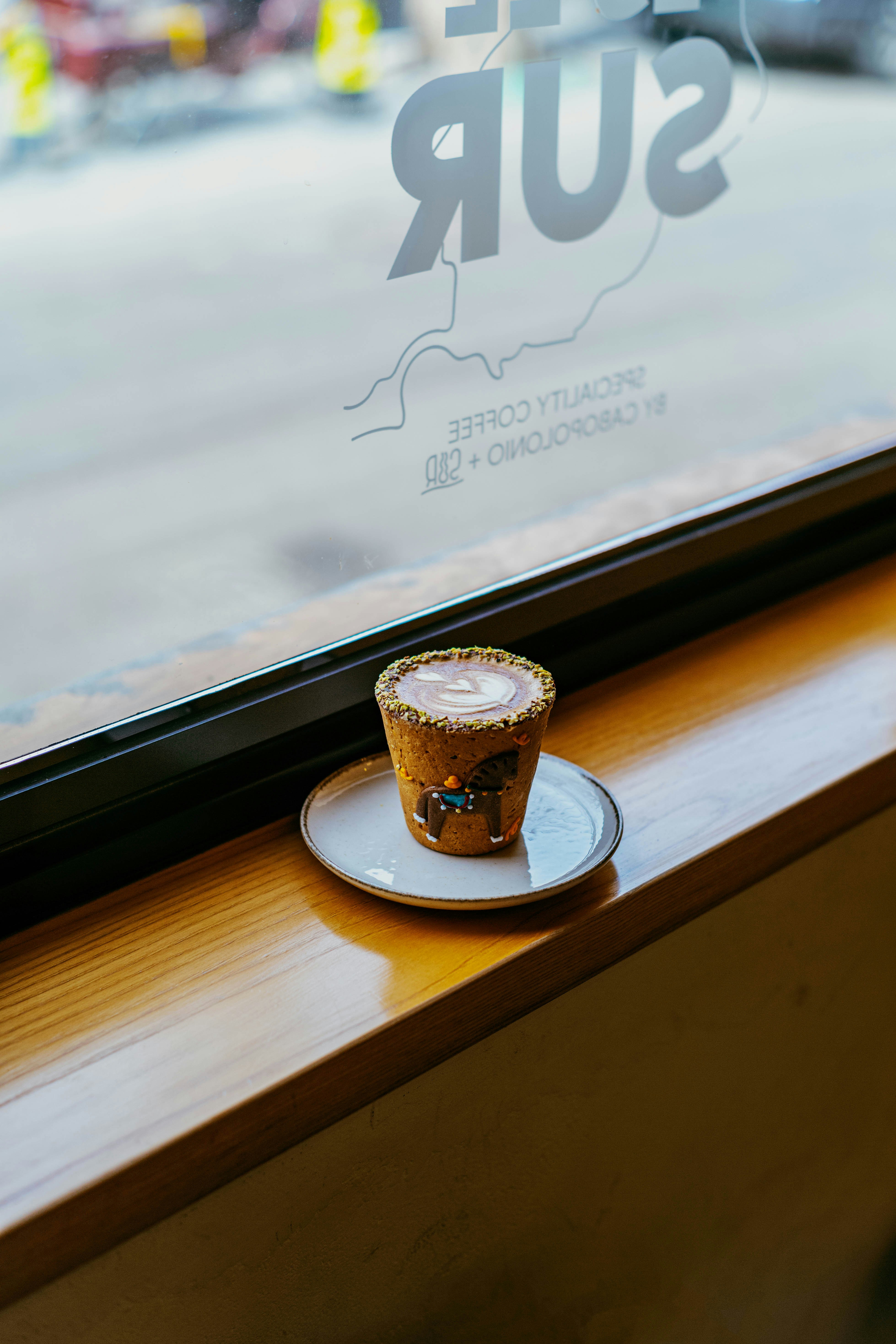 Café avec un latte art sur une soucoupe près de la fenêtre.