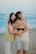 Family posing on a beach with the ocean behind them
