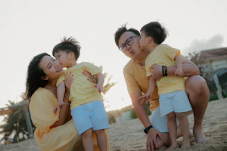 Family in yellow outfits on a beach at sunset