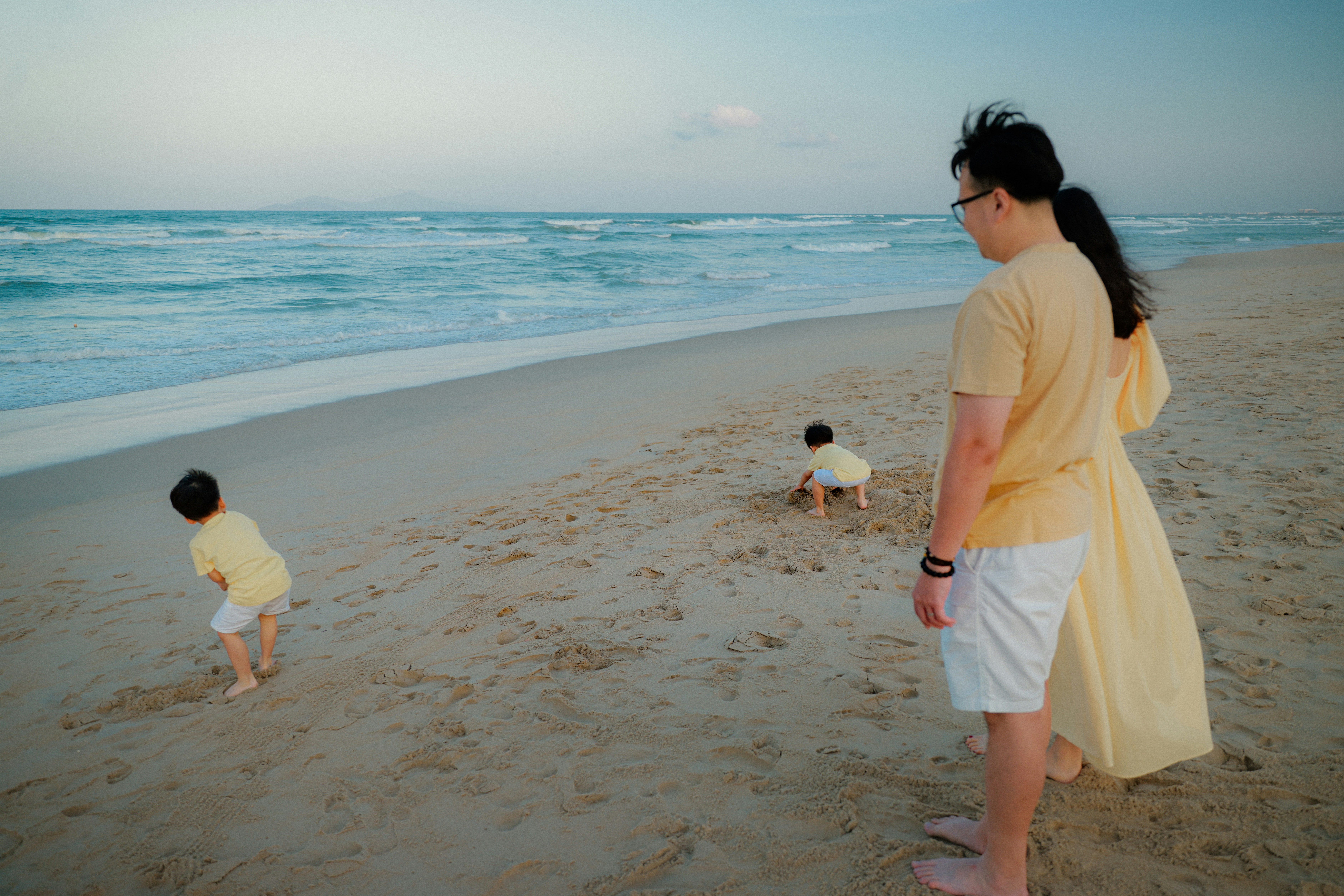 Family on a sandy beach near the ocean waves.