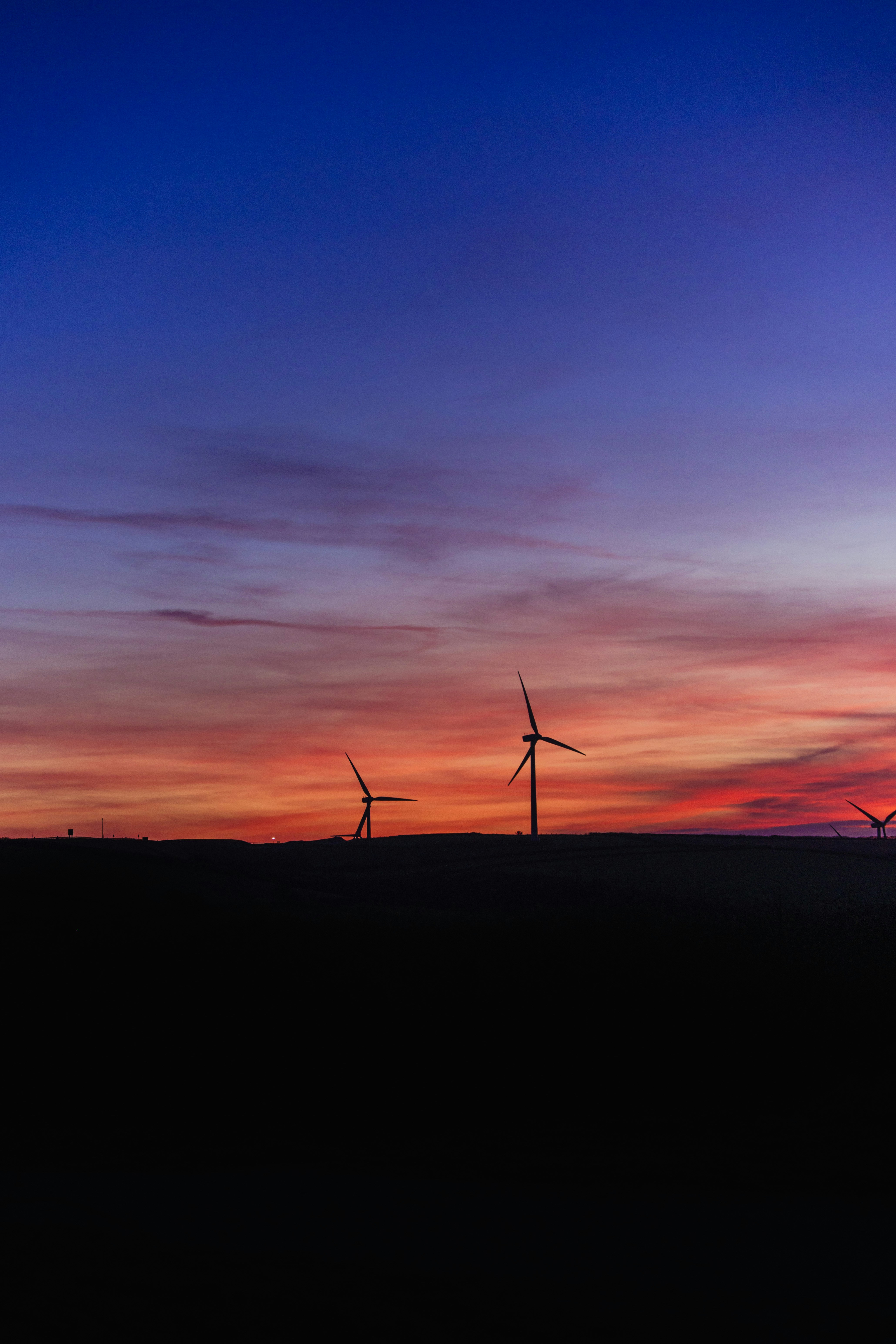 Wind turbines silhouetted against a vibrant sunset sky.