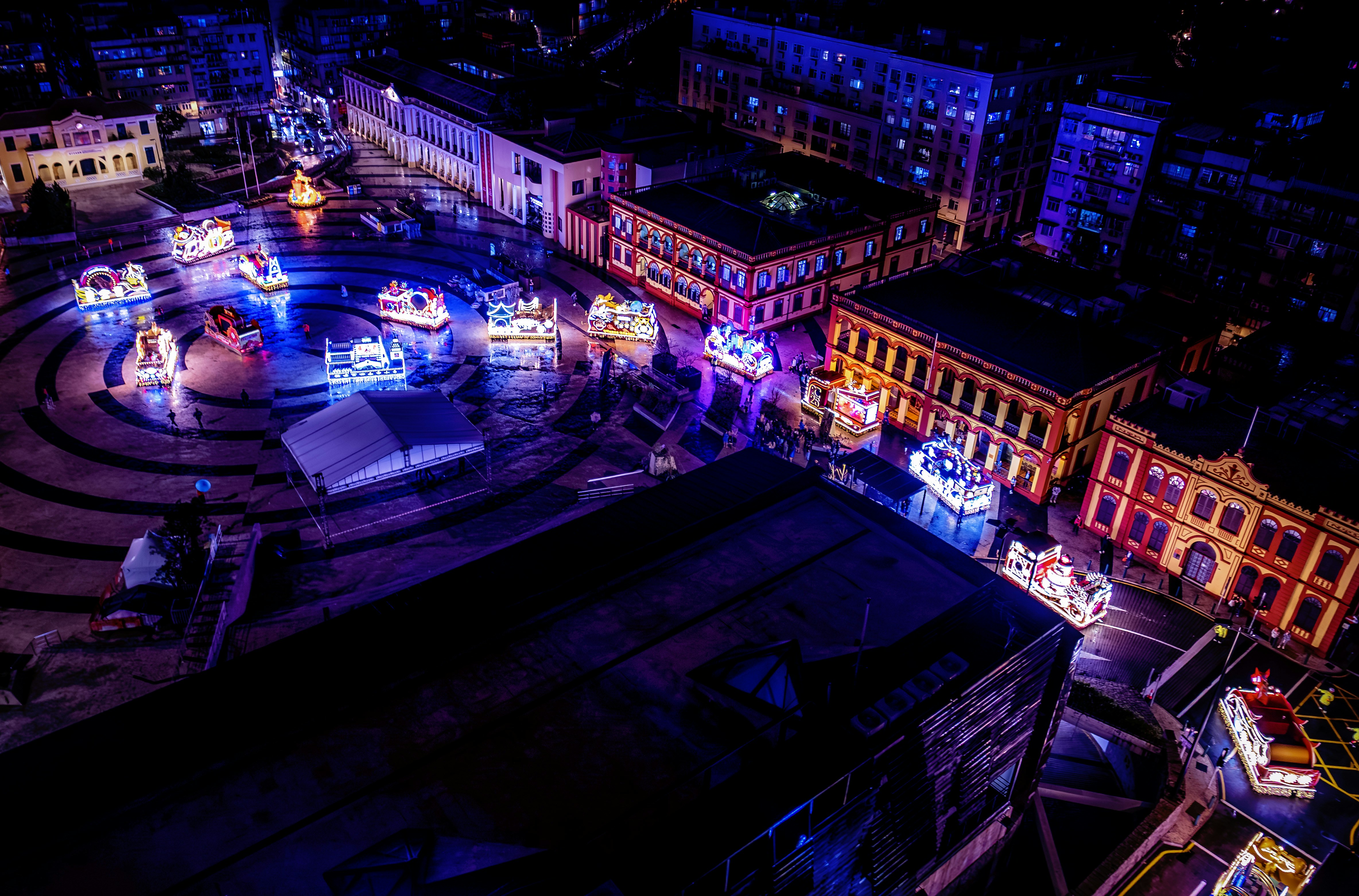 Festive illuminated square at night with buildings.