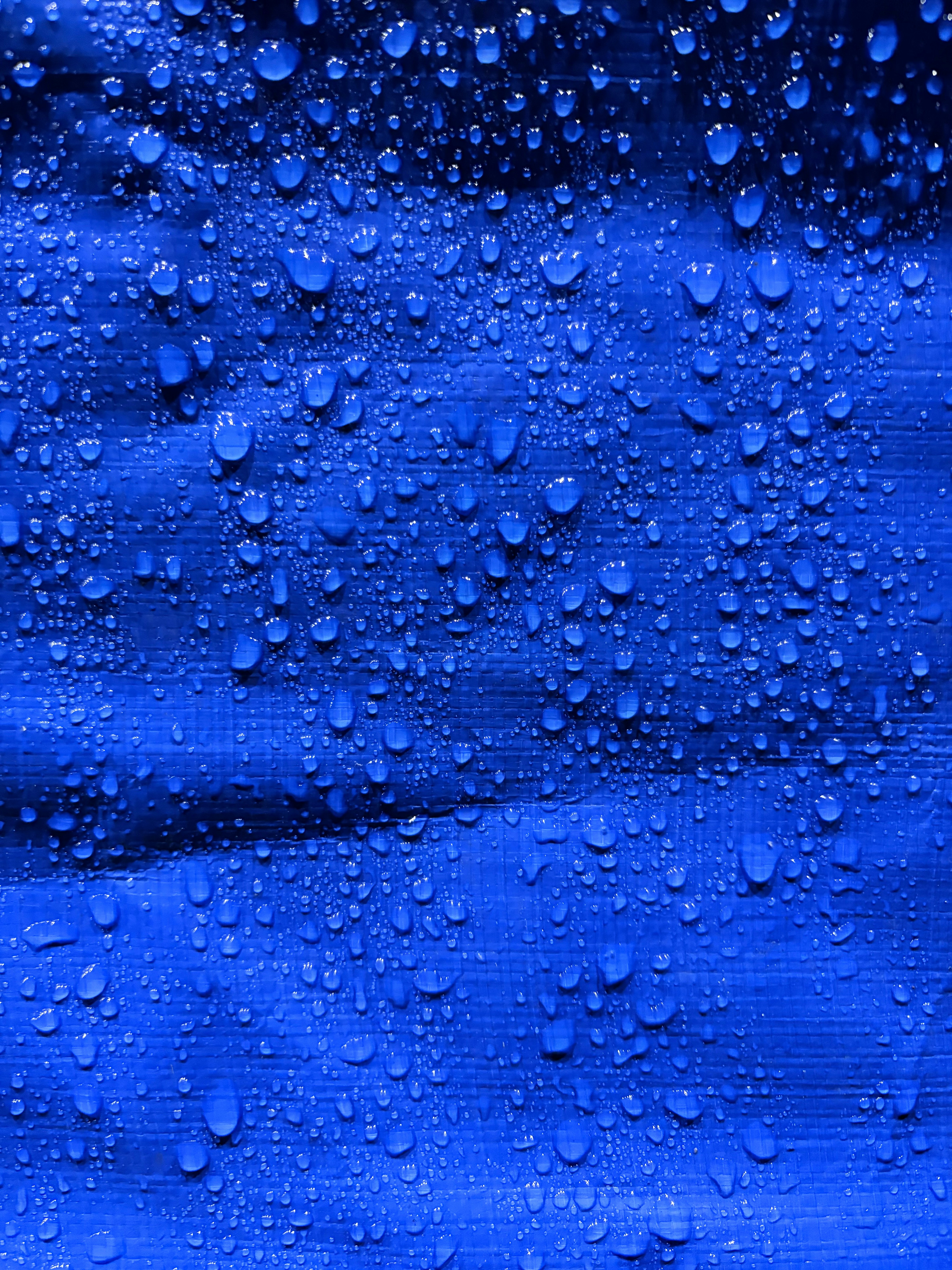 Close-up of water droplets on a blue textured surface.