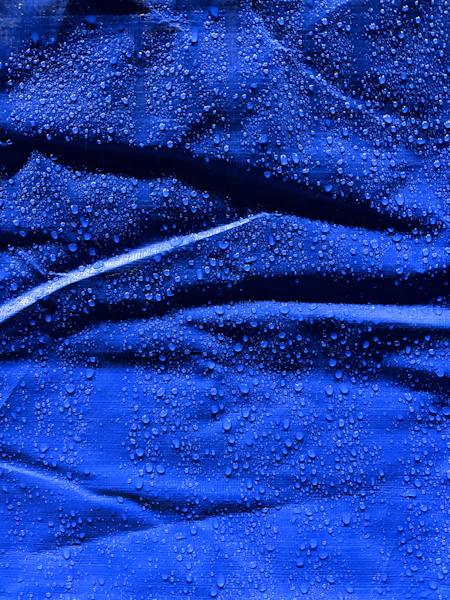 Water droplets beading on a textured waterproof jacket fabric