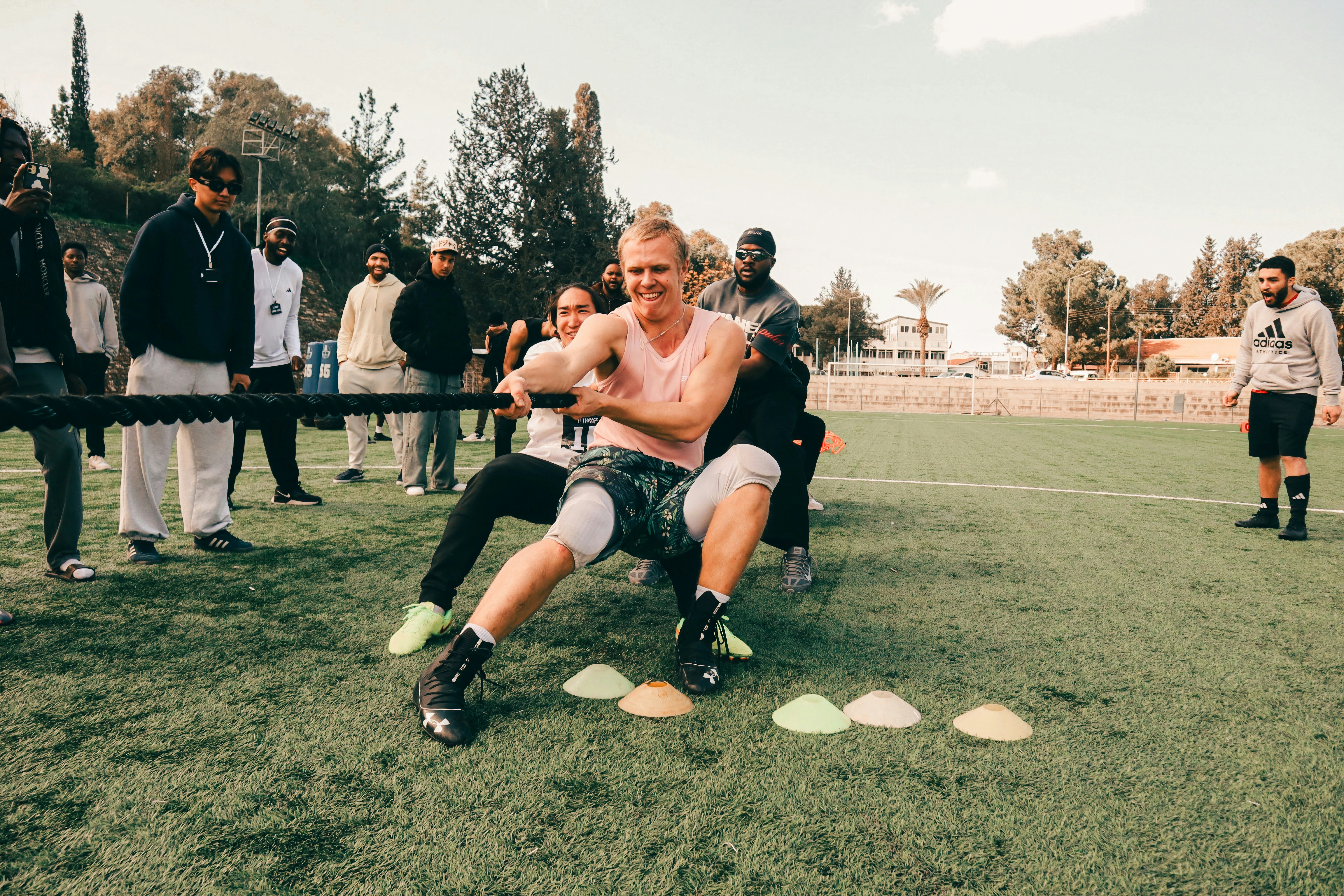 People playing tug-of-war on a grassy field.