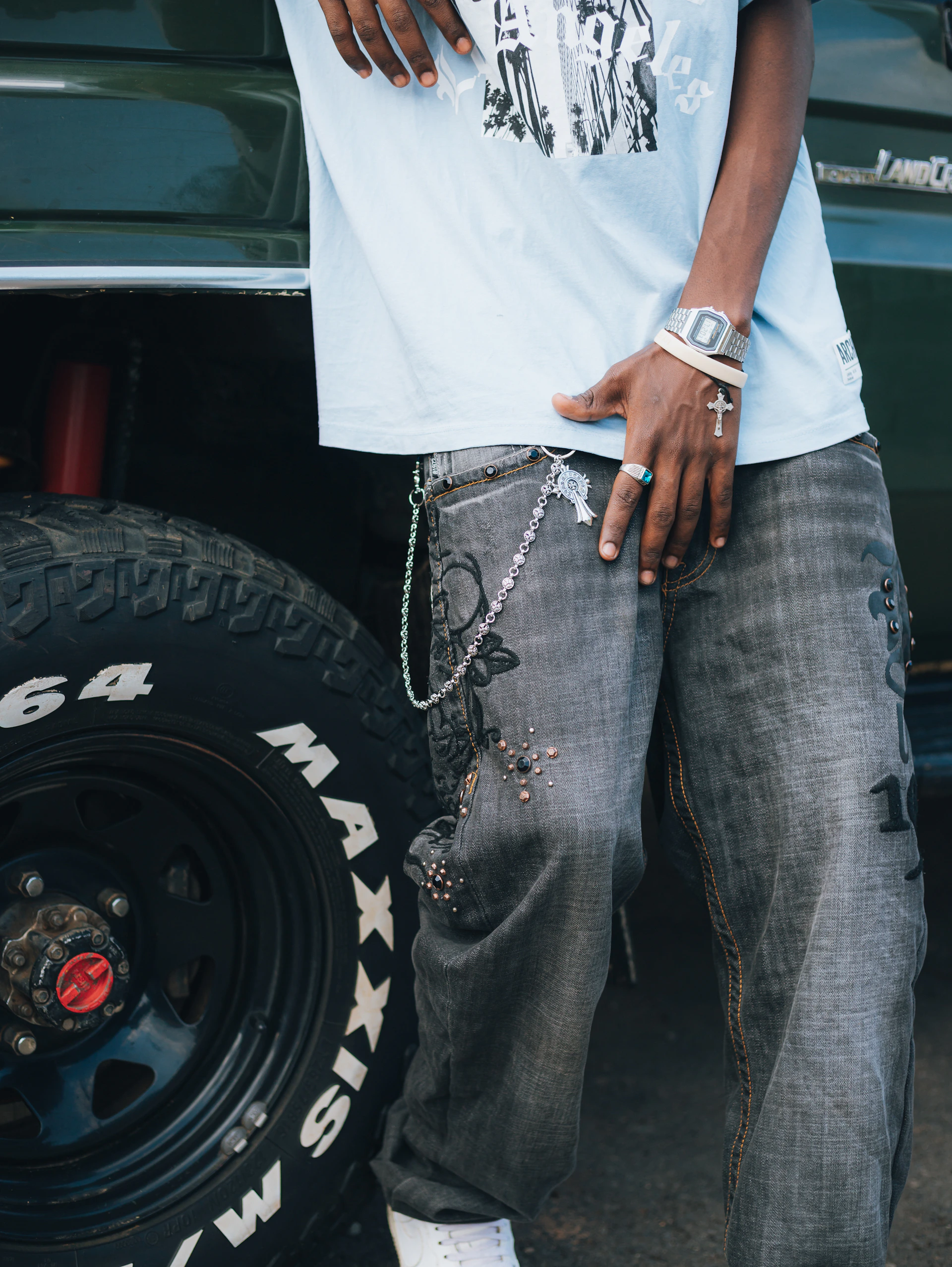Person wearing jeans and standing next to a vehicle