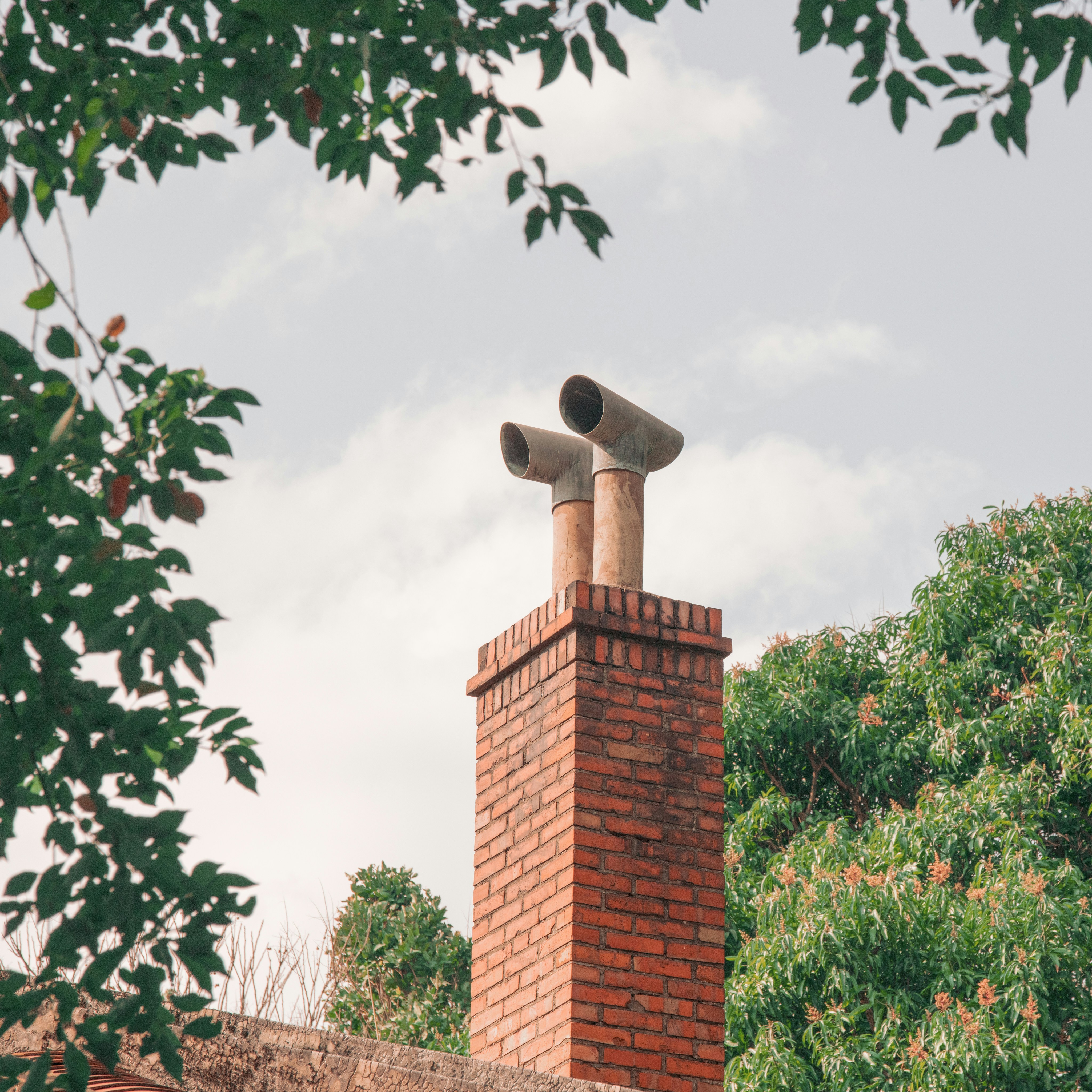 Brick chimney with twin pipes against cloudy sky