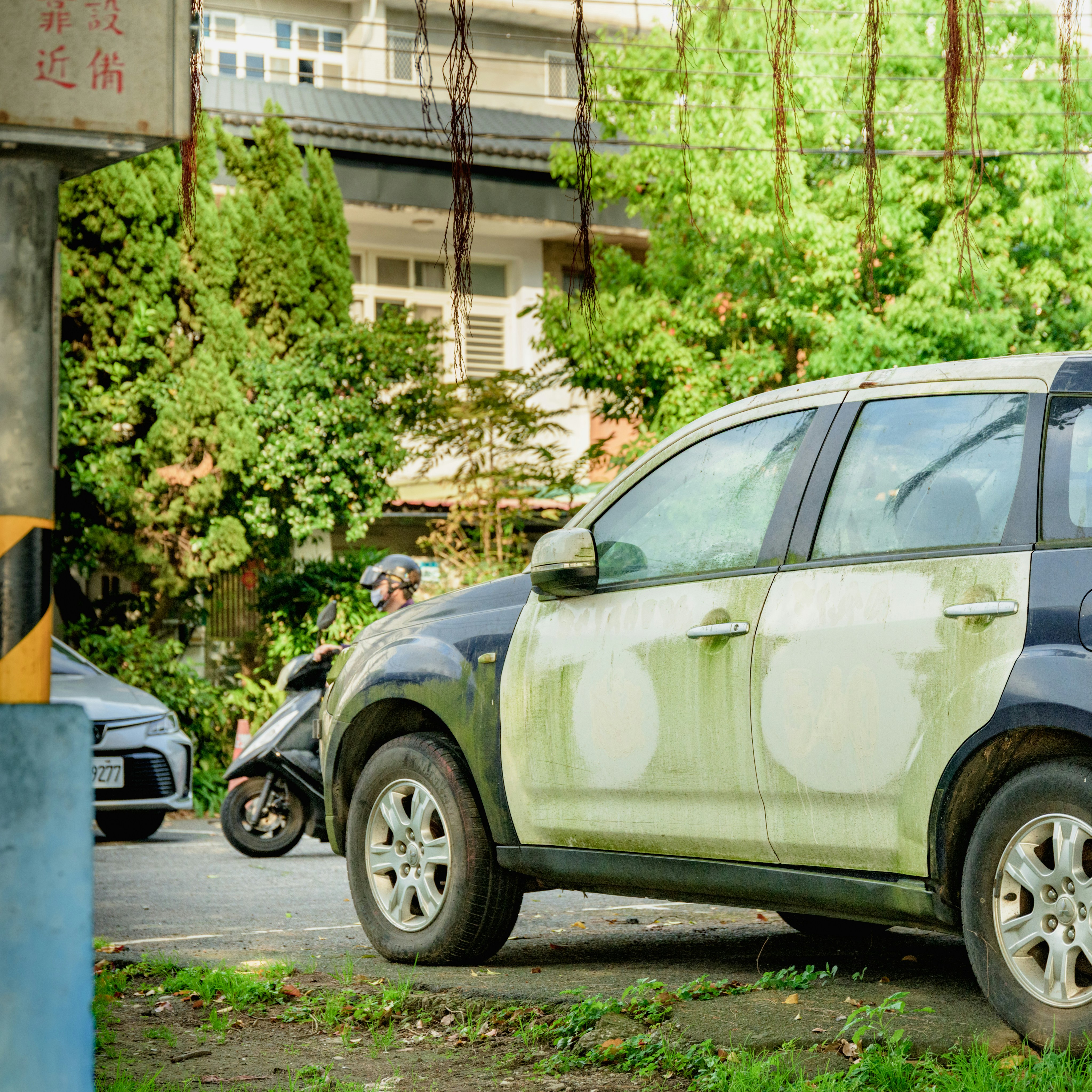 A car with faded paint parked on a street.