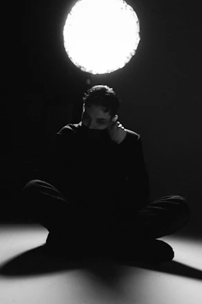 Man sitting in a dark room with a spotlight.