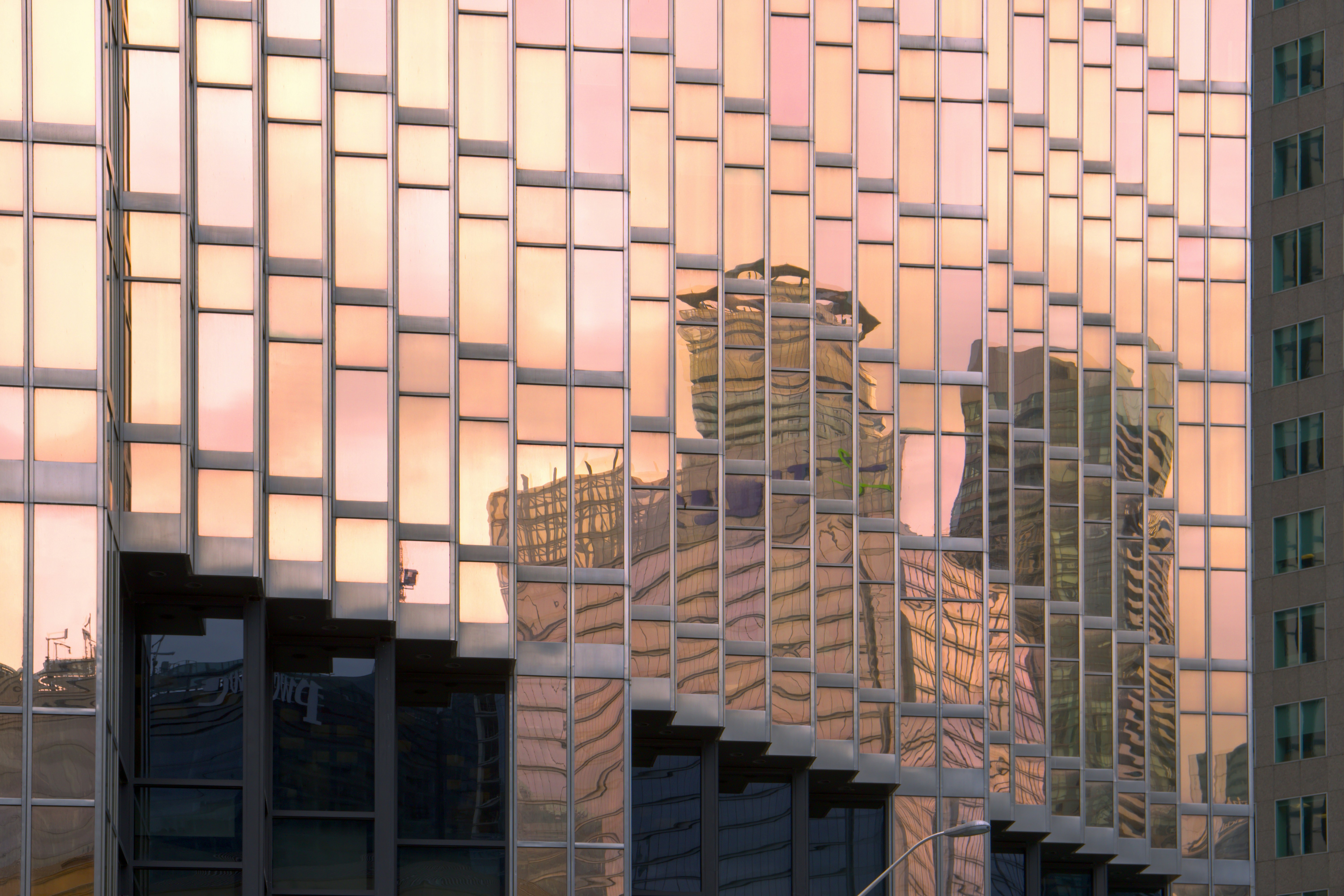 Edificio de cristal que refleja el cielo y los edificios del atardecer