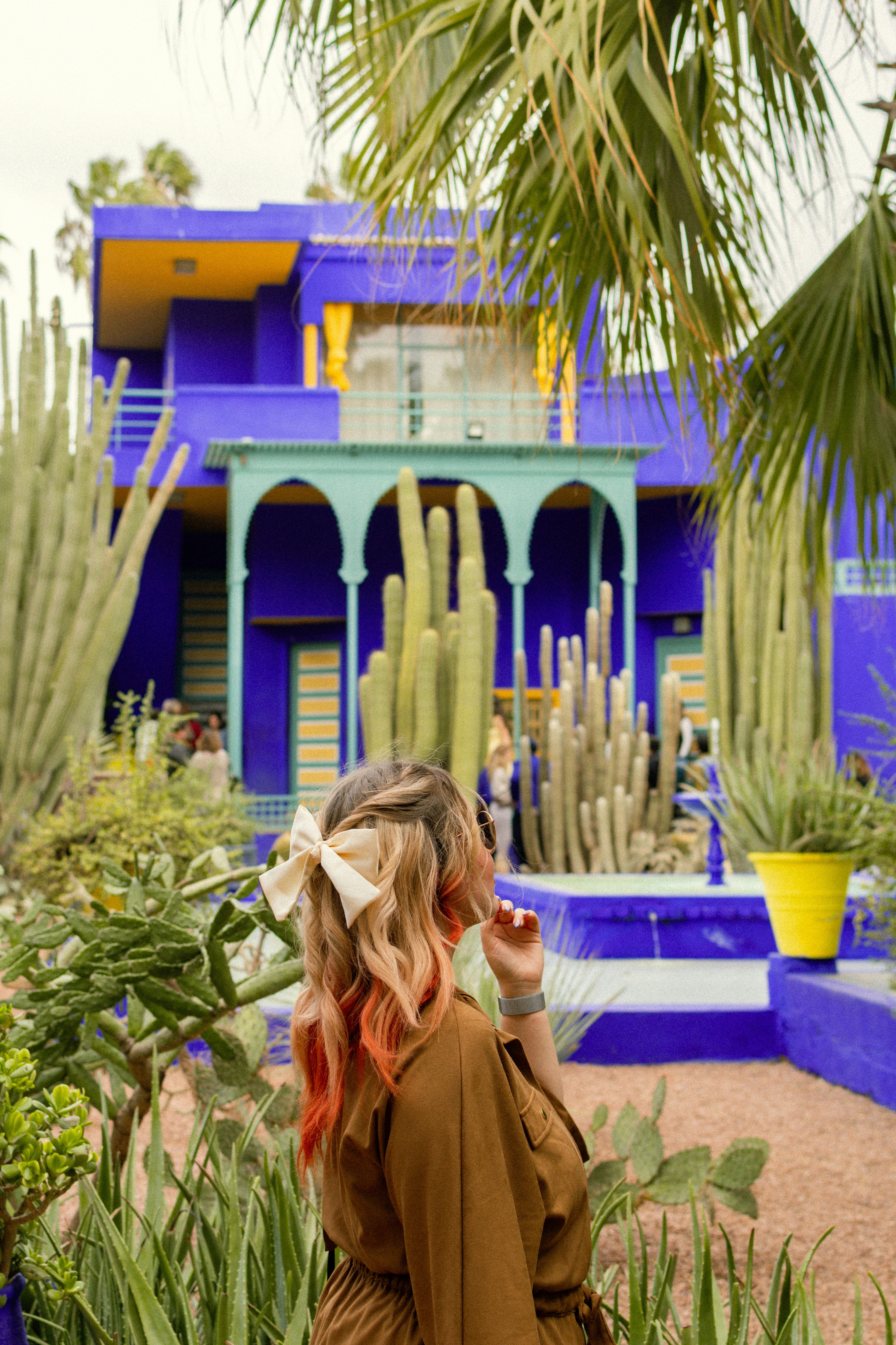 Woman with colorful hair in exotic garden with blue building