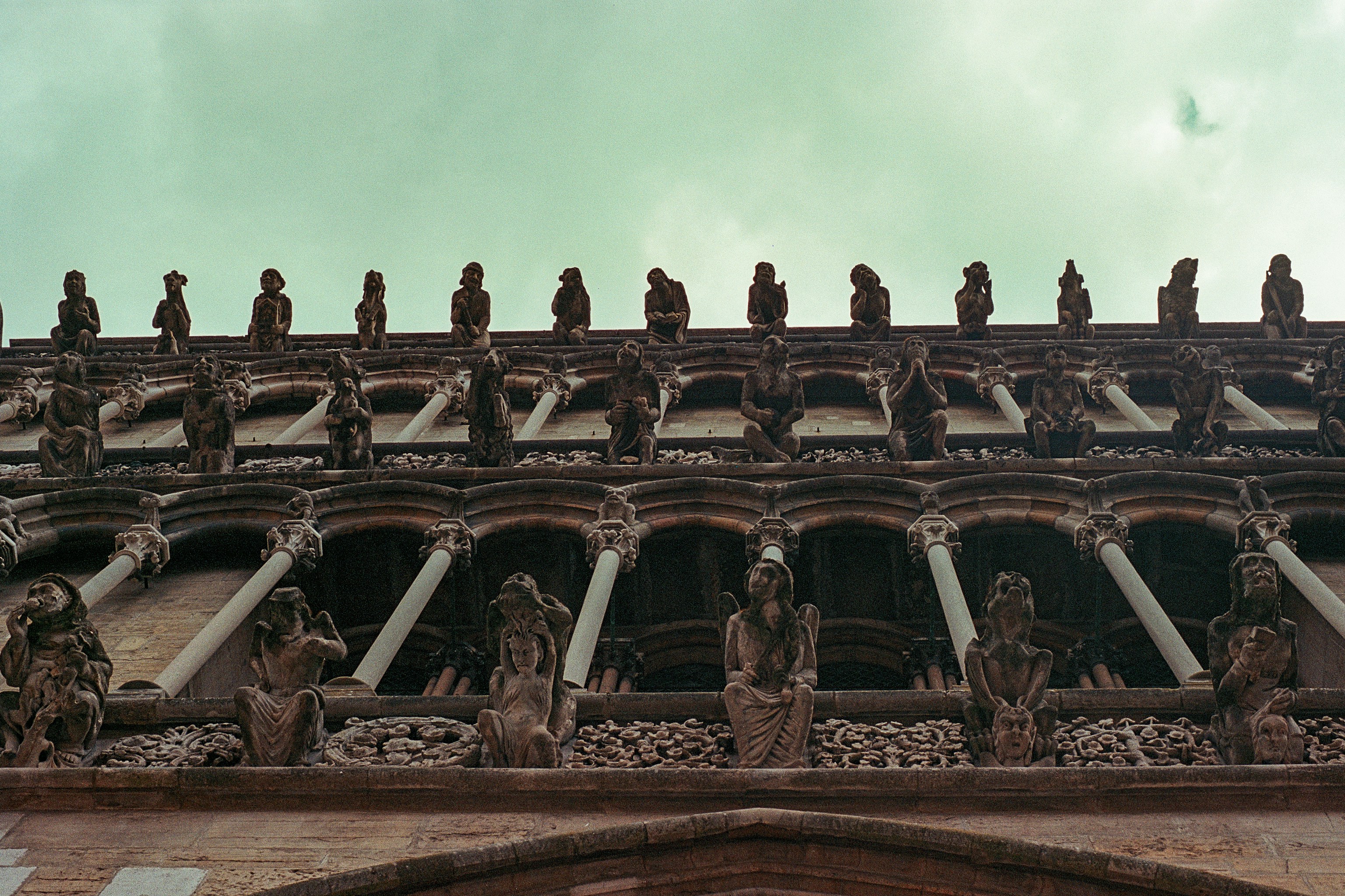 Gargoyles line the roof of an old stone building.