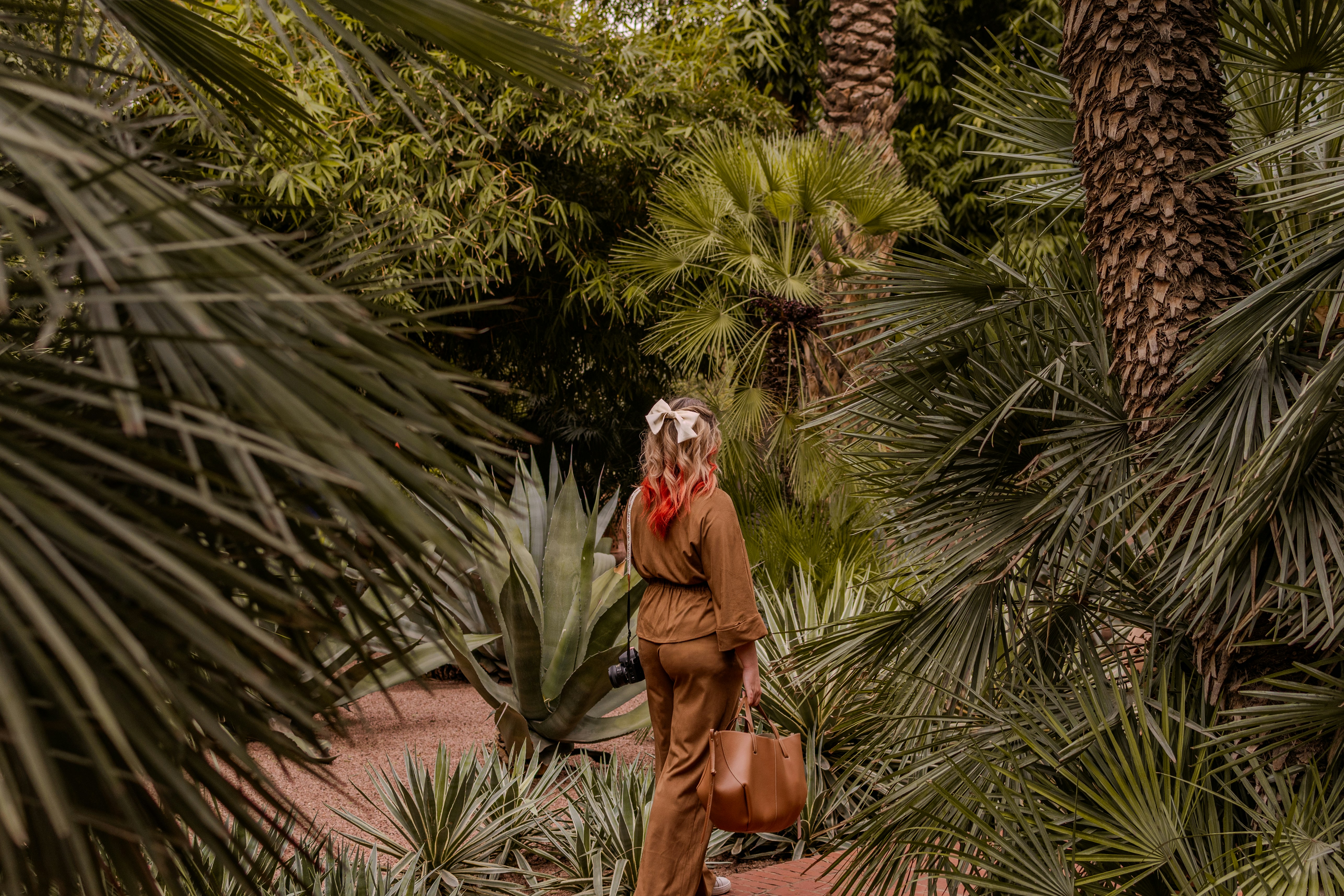 Woman walking through a lush green botanical garden.
