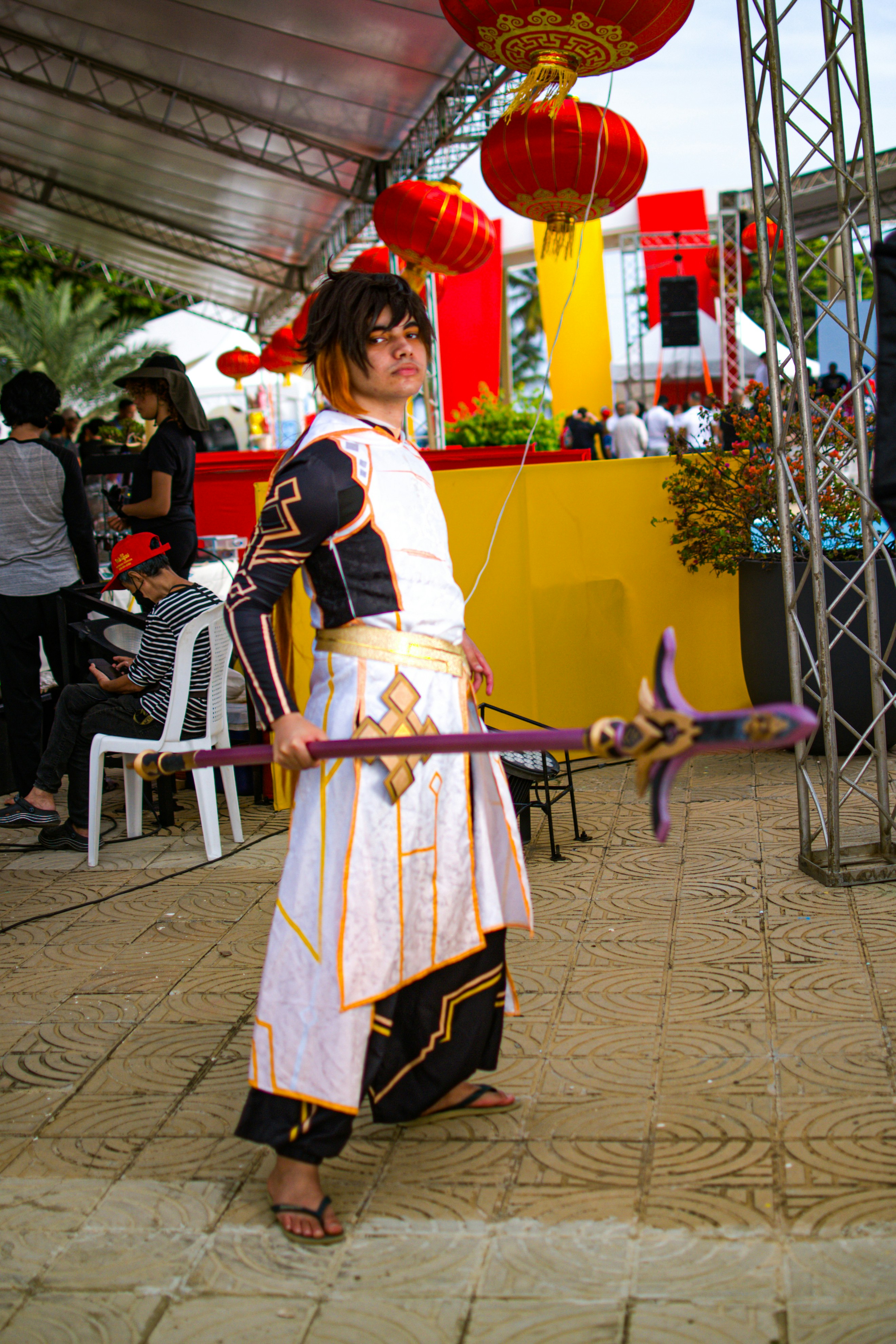 Cosplayer dengan kostum hiasan memegang tongkat dengan lentera merah