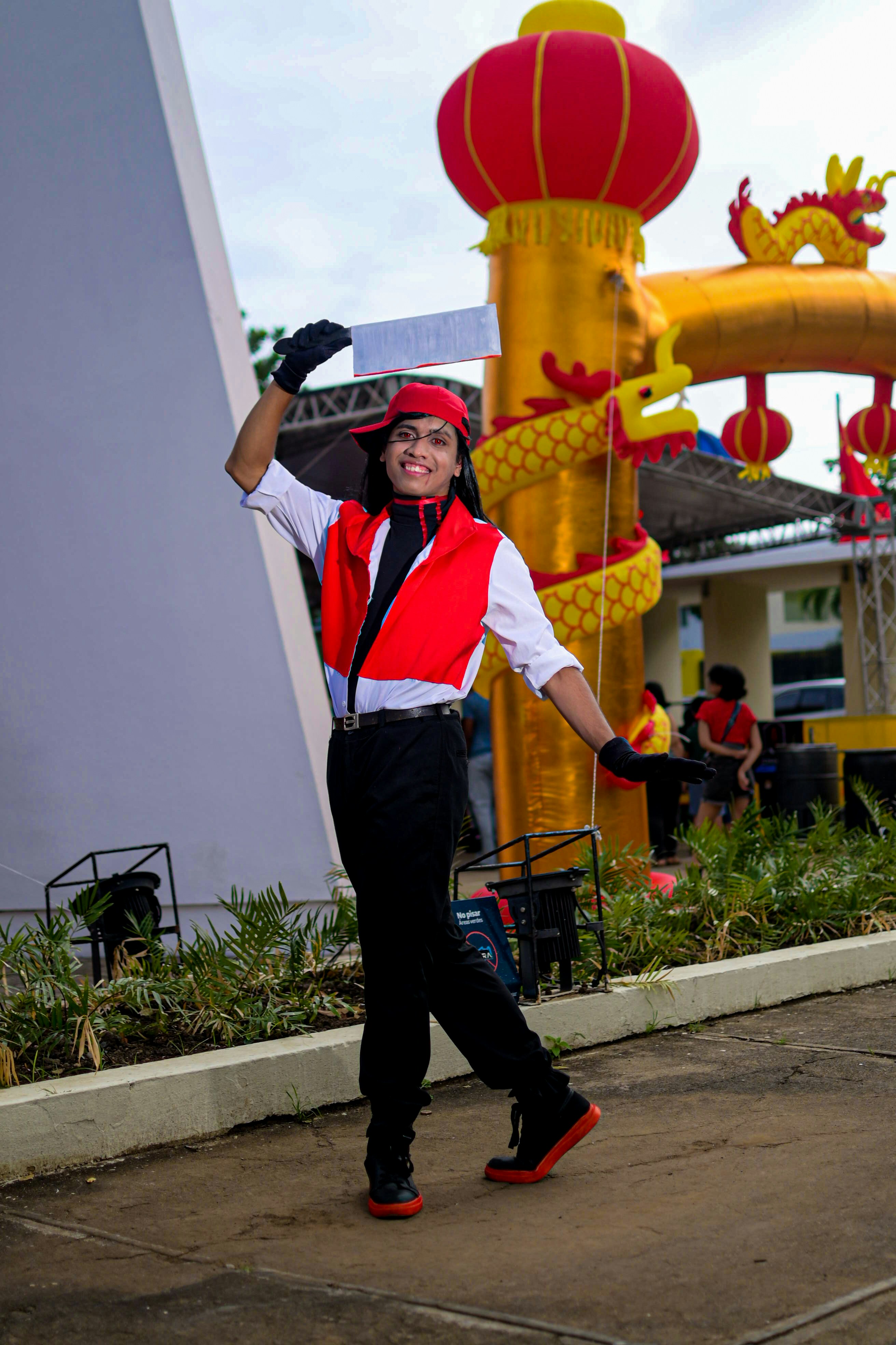 Pria dengan rompi merah dan celana hitam menari di luar ruangan.