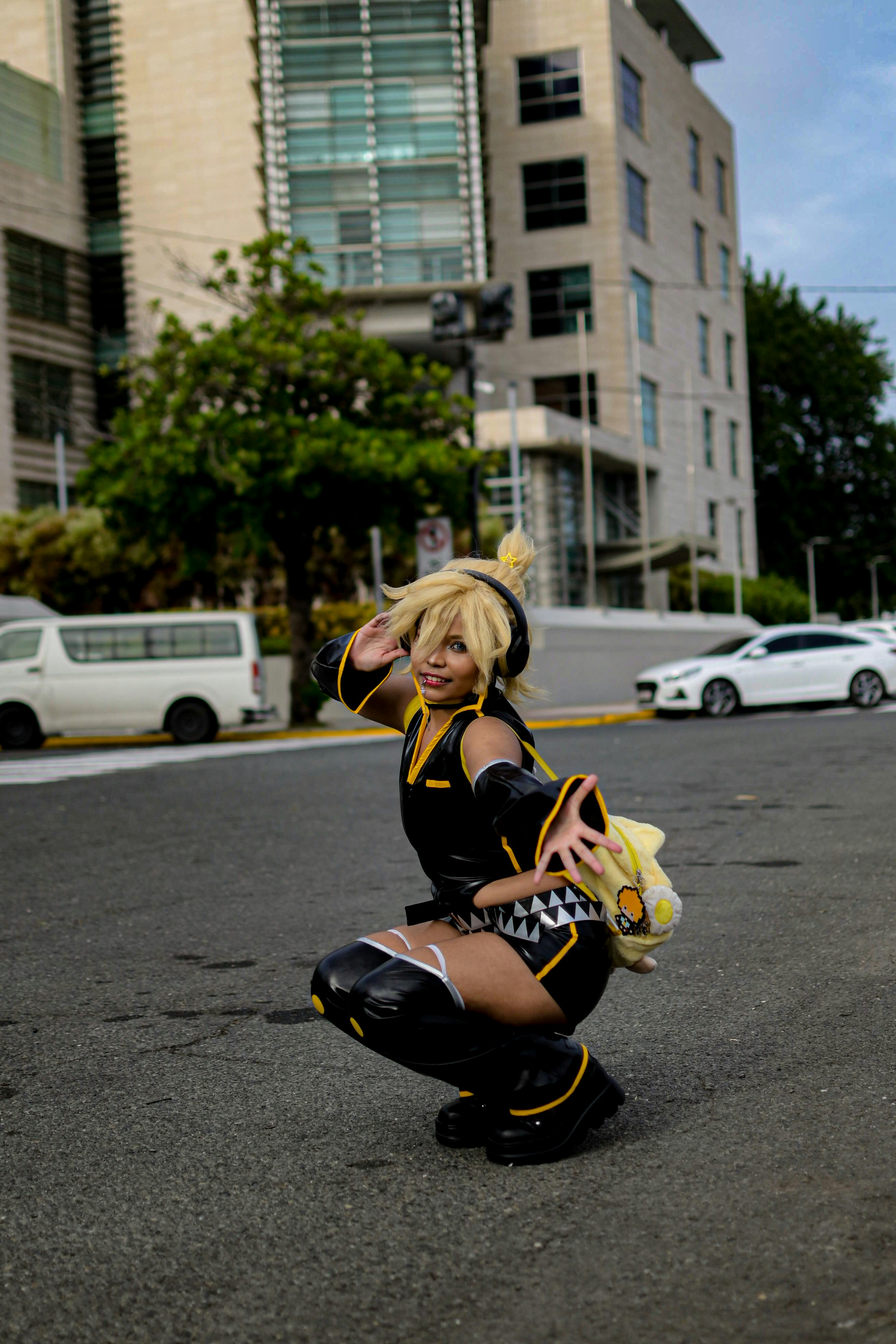 Cosplayer dengan pakaian kuning dan hitam berpose di jalan