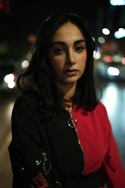 Woman in a red and black jacket at night