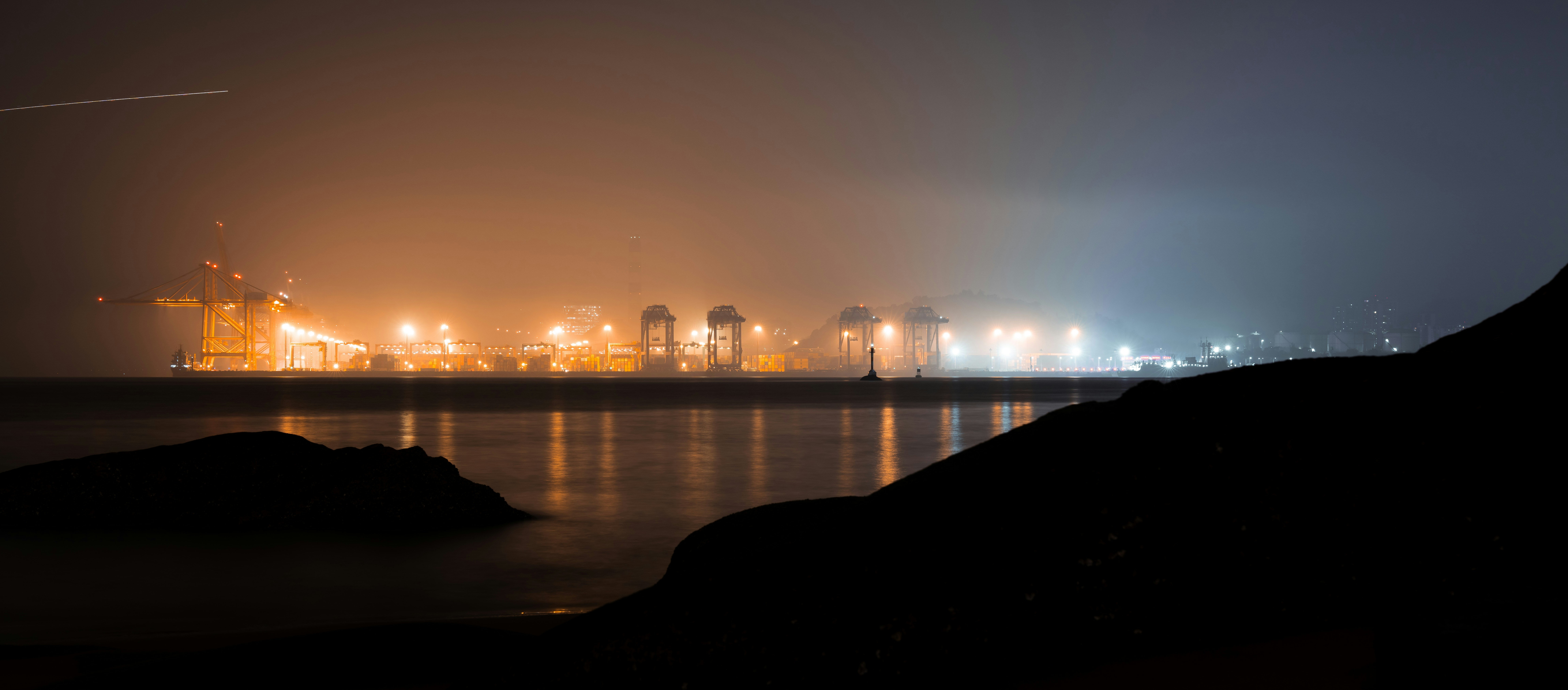 Puerto industrial con grúas iluminadas por la noche