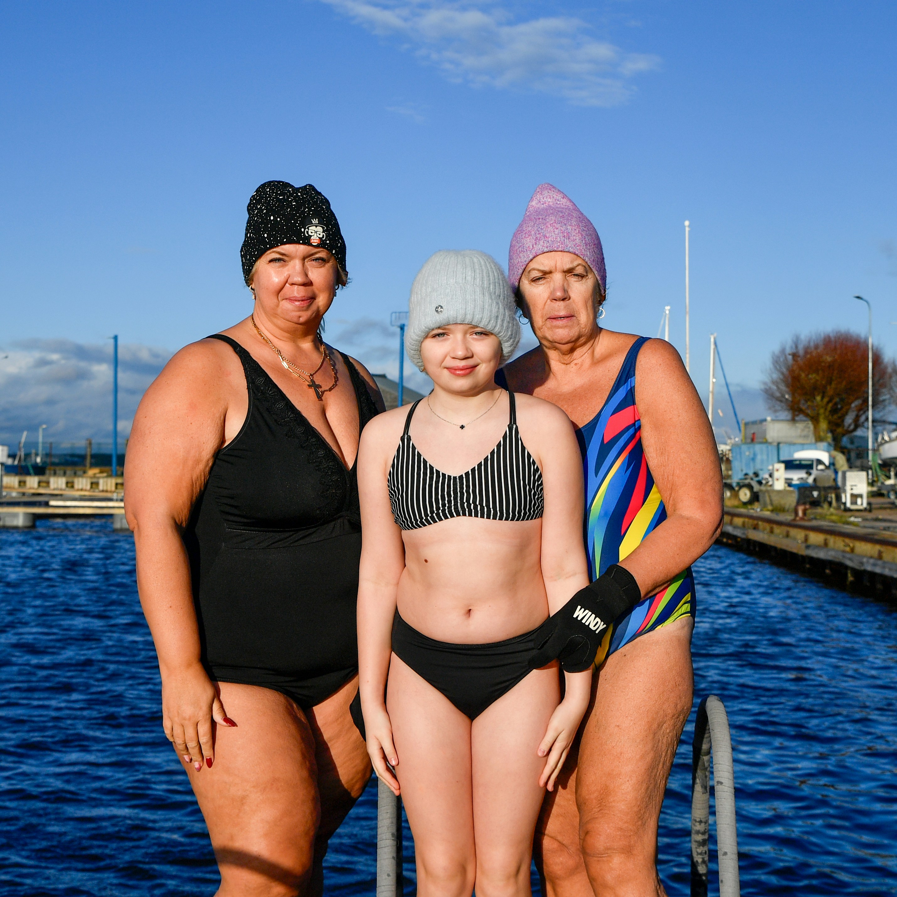 Three women in swimwear by the water
