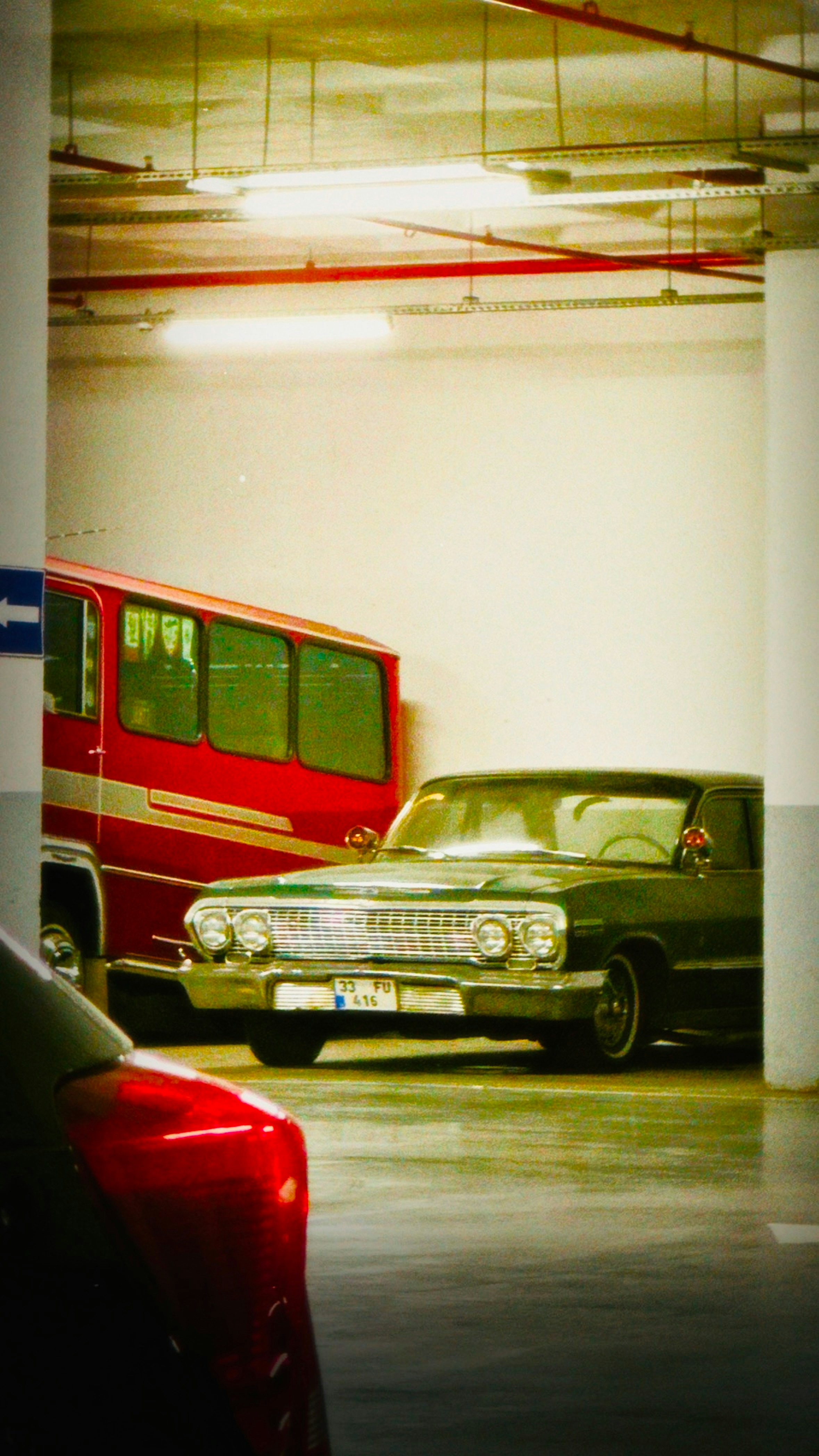 Green vintage car parked next to a red bus