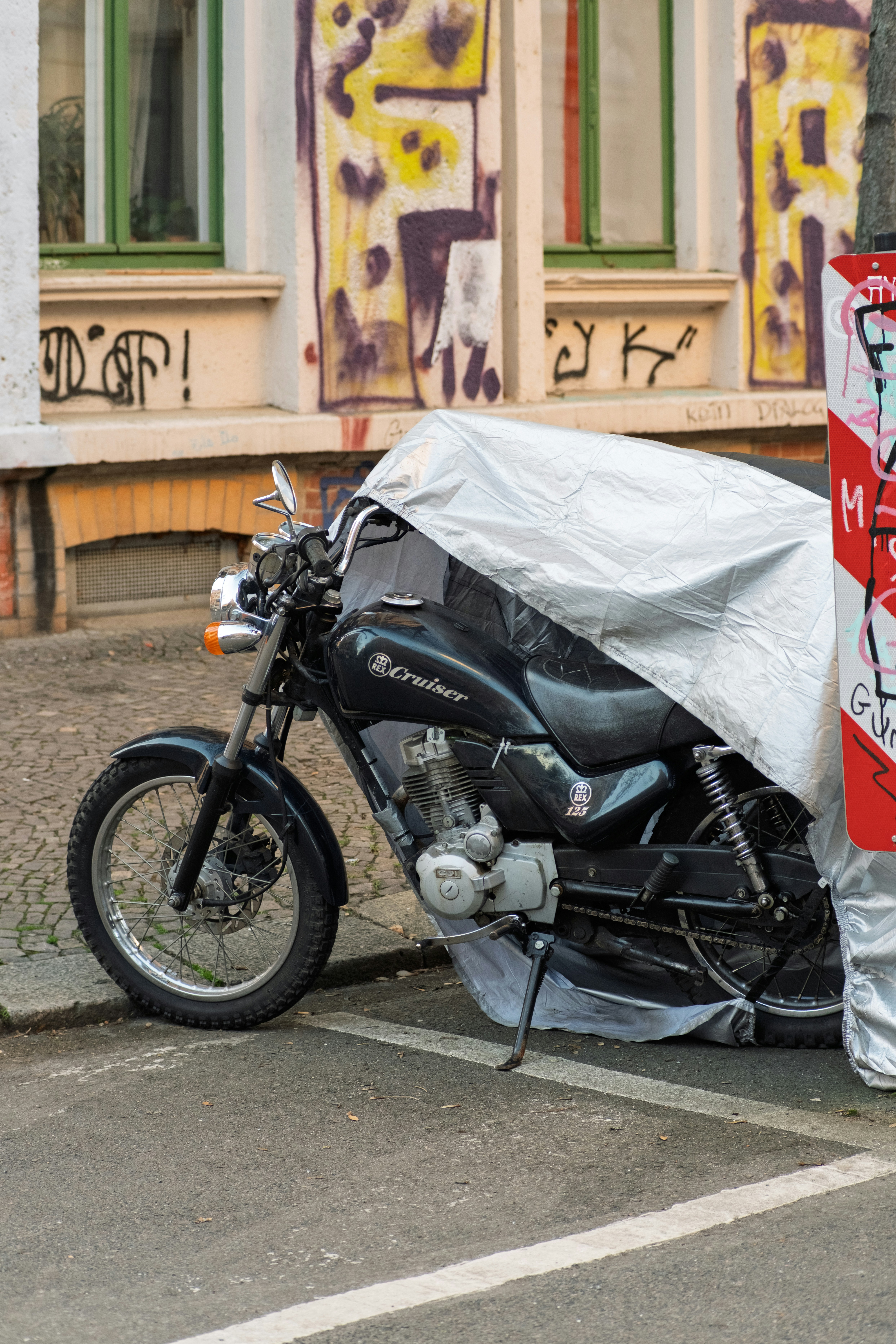 Ein schwarzes Motorrad, bedeckt mit einer silbernen Plane.