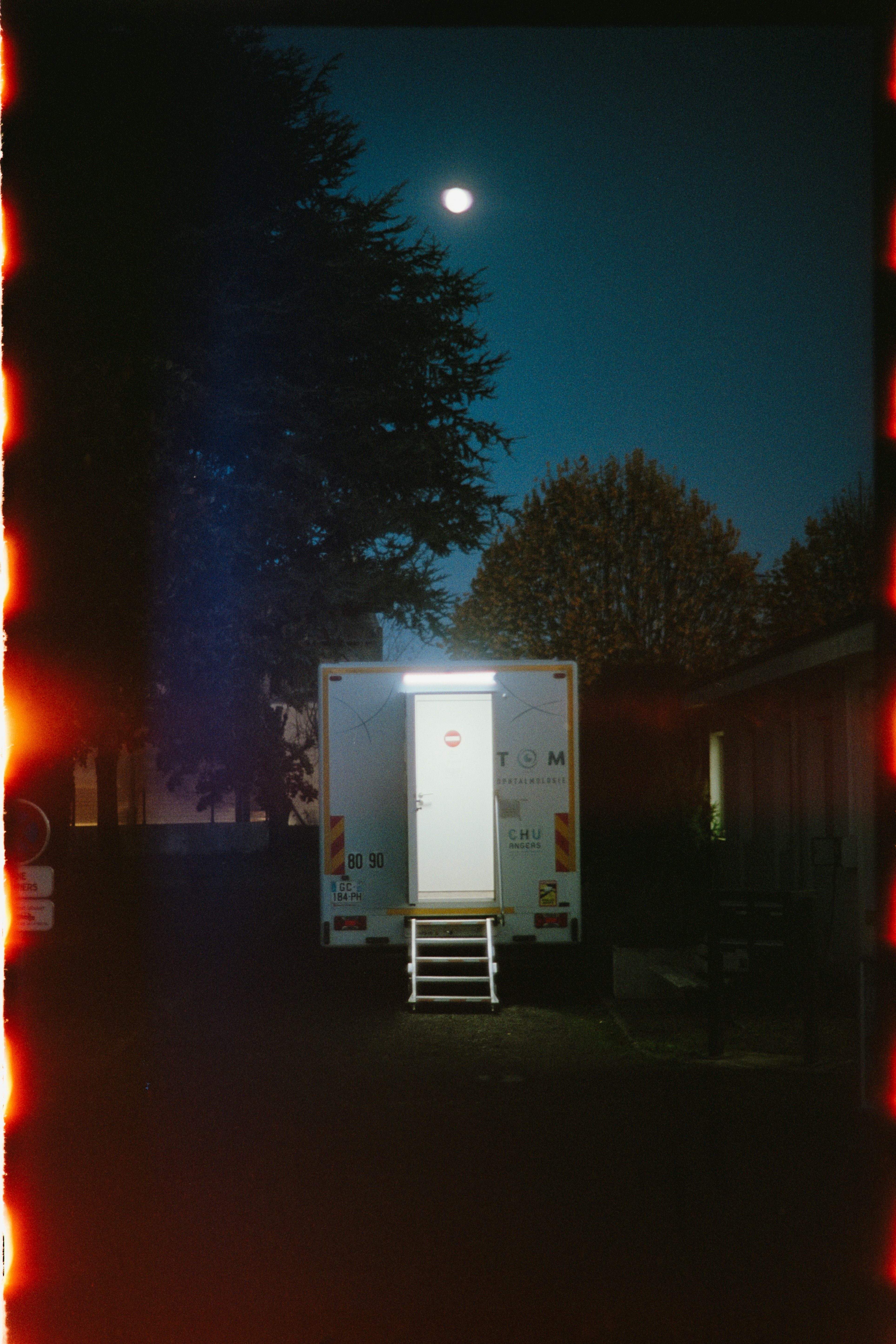 Des toilettes portables éclairées la nuit sous la lune.