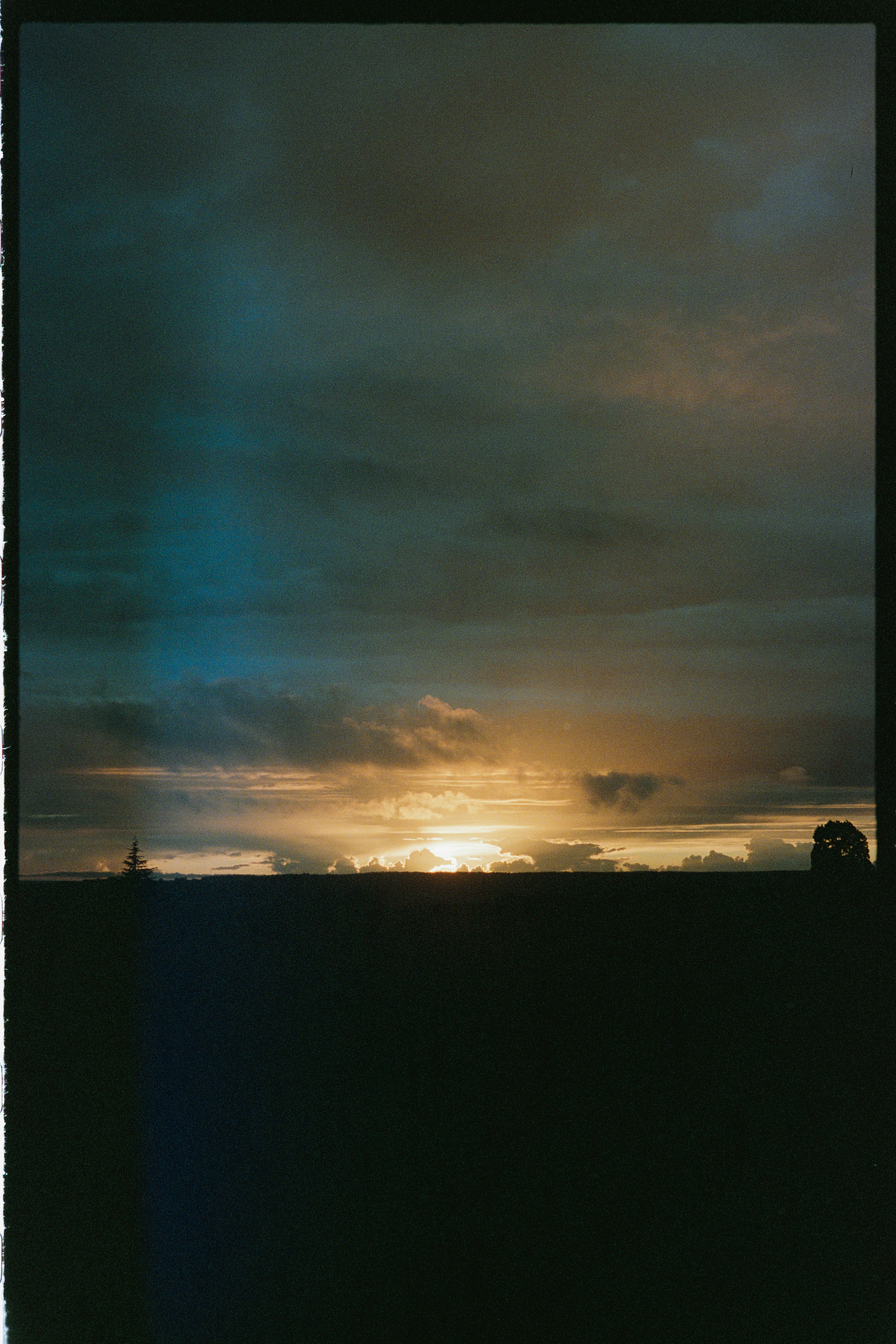 Un coucher de soleil dramatique sur un paysage sombre et silhouetté.