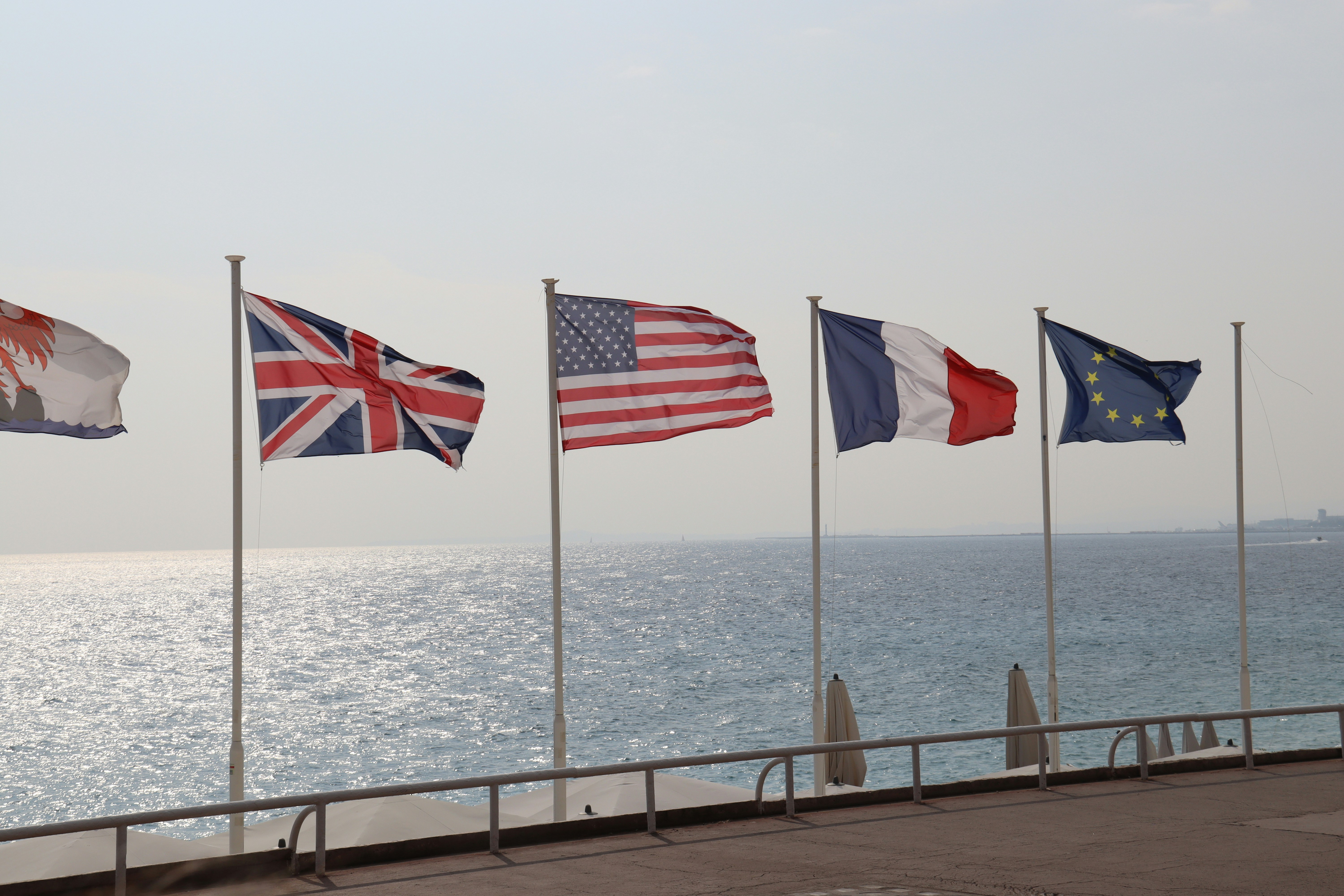 Banderas de diferentes naciones ondean junto al océano.