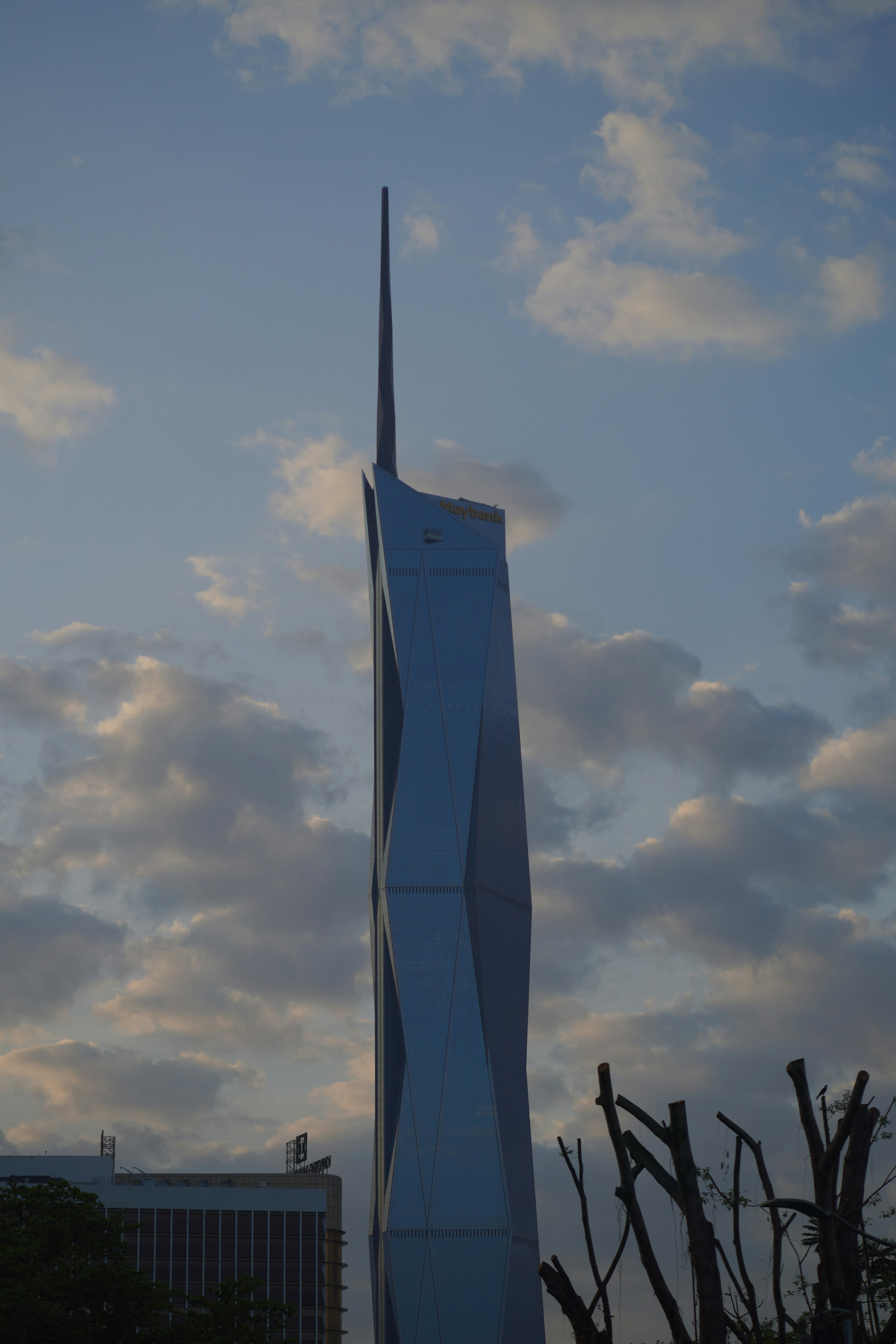 Arranha-céu moderno com torre única contra céu nublado