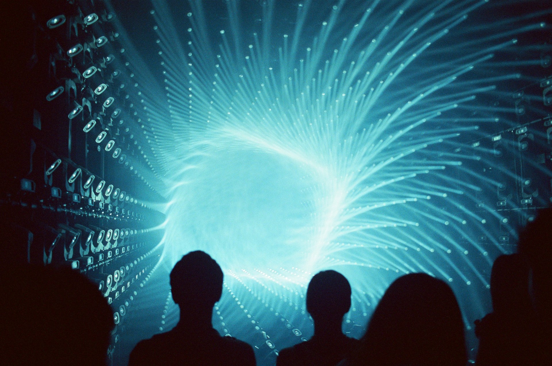 Silhouettes of people watching a bright blue swirling vortex