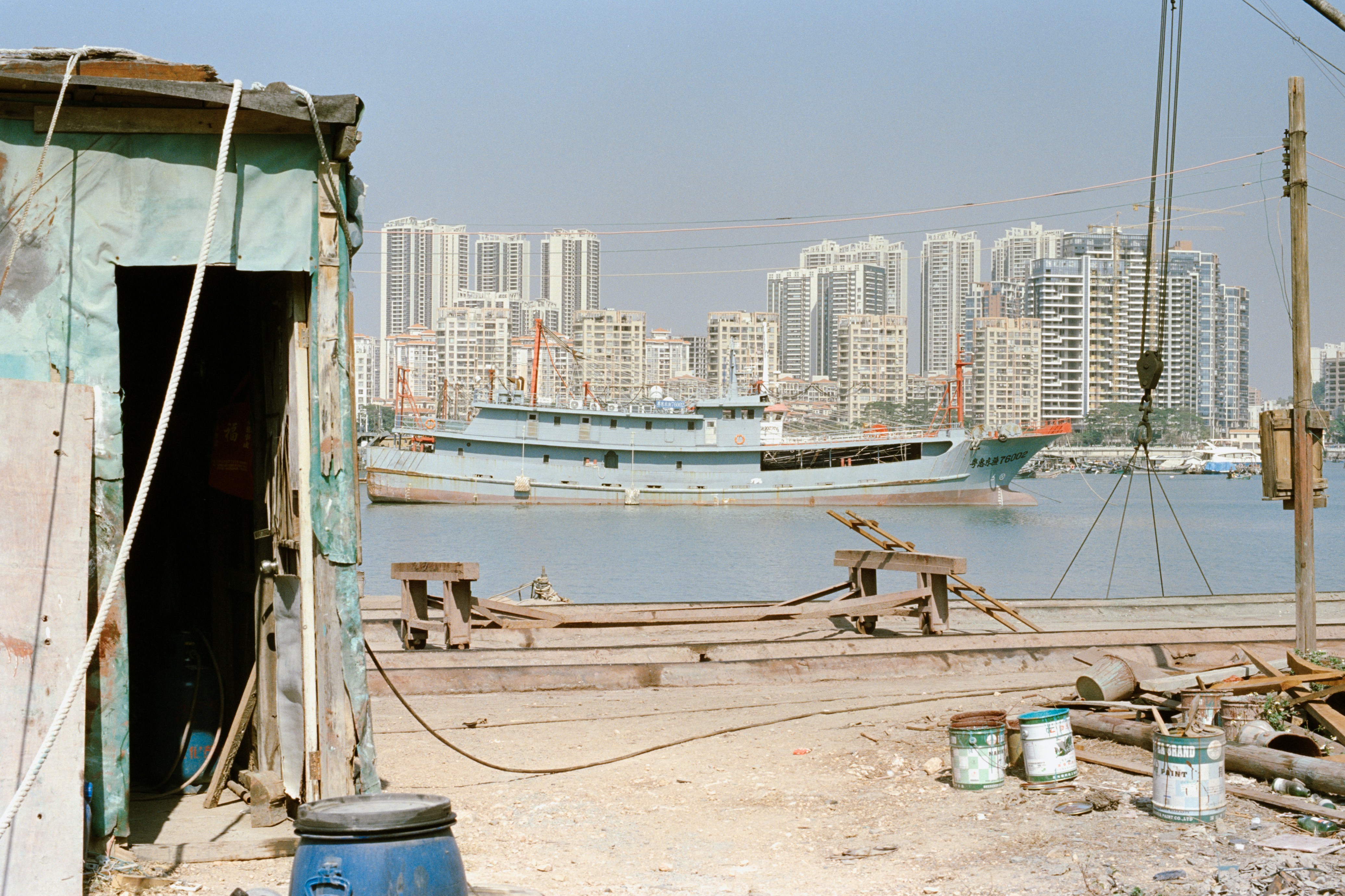 A light blue boat docked near a city skyline.