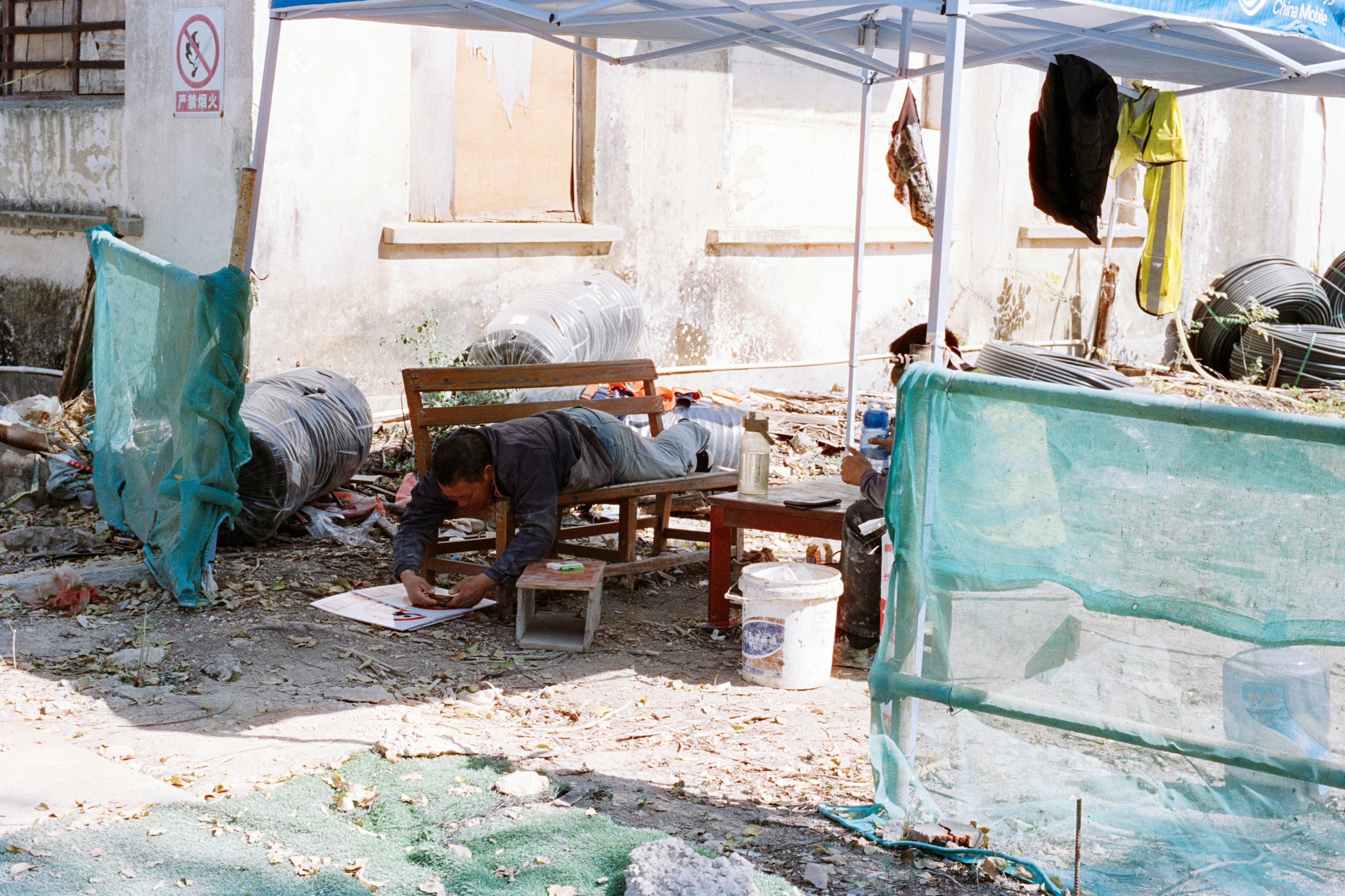 Man lying down drawing on paper under tent