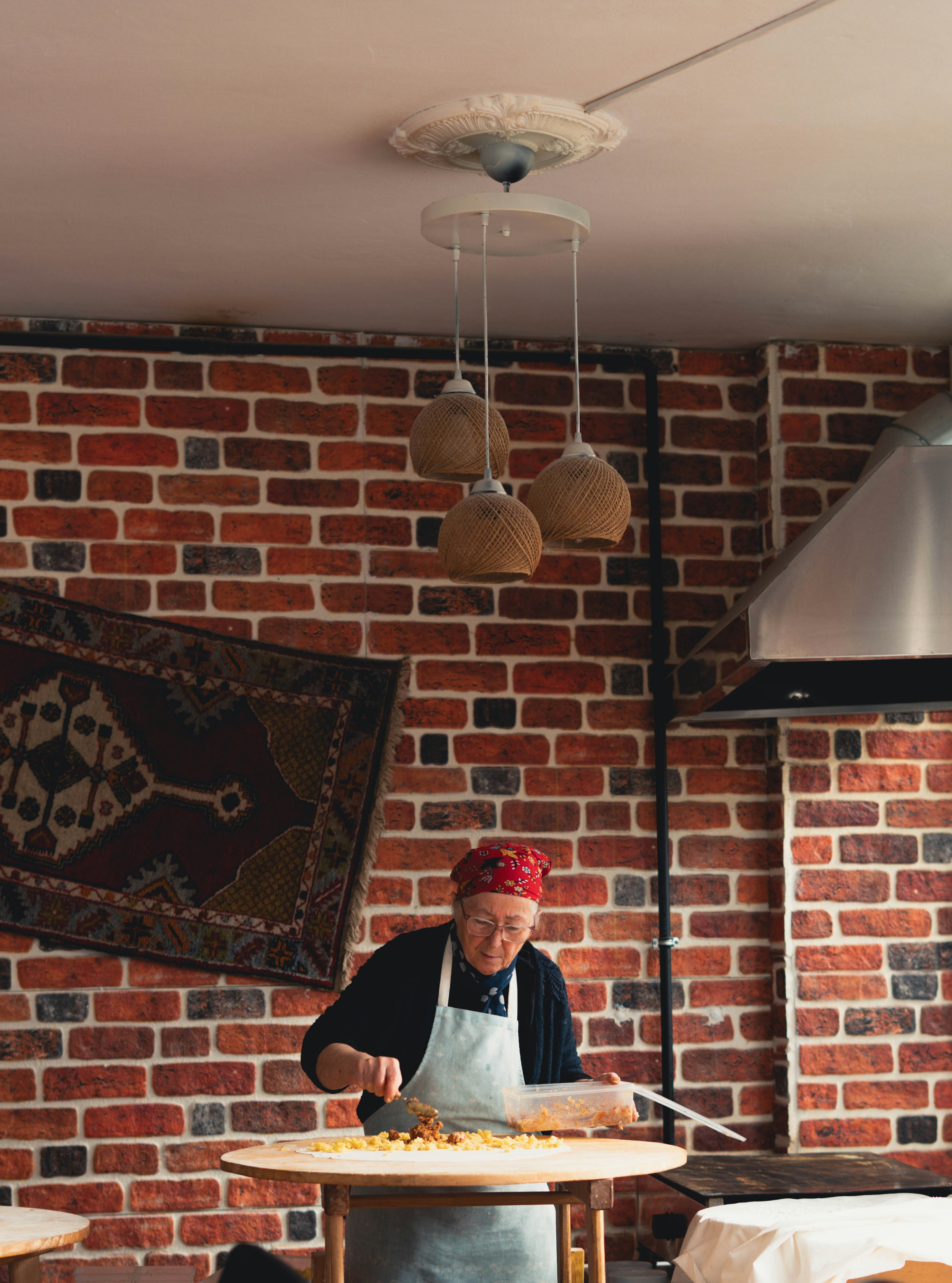 Mujer mayor preparando comida en una mesa redonda.